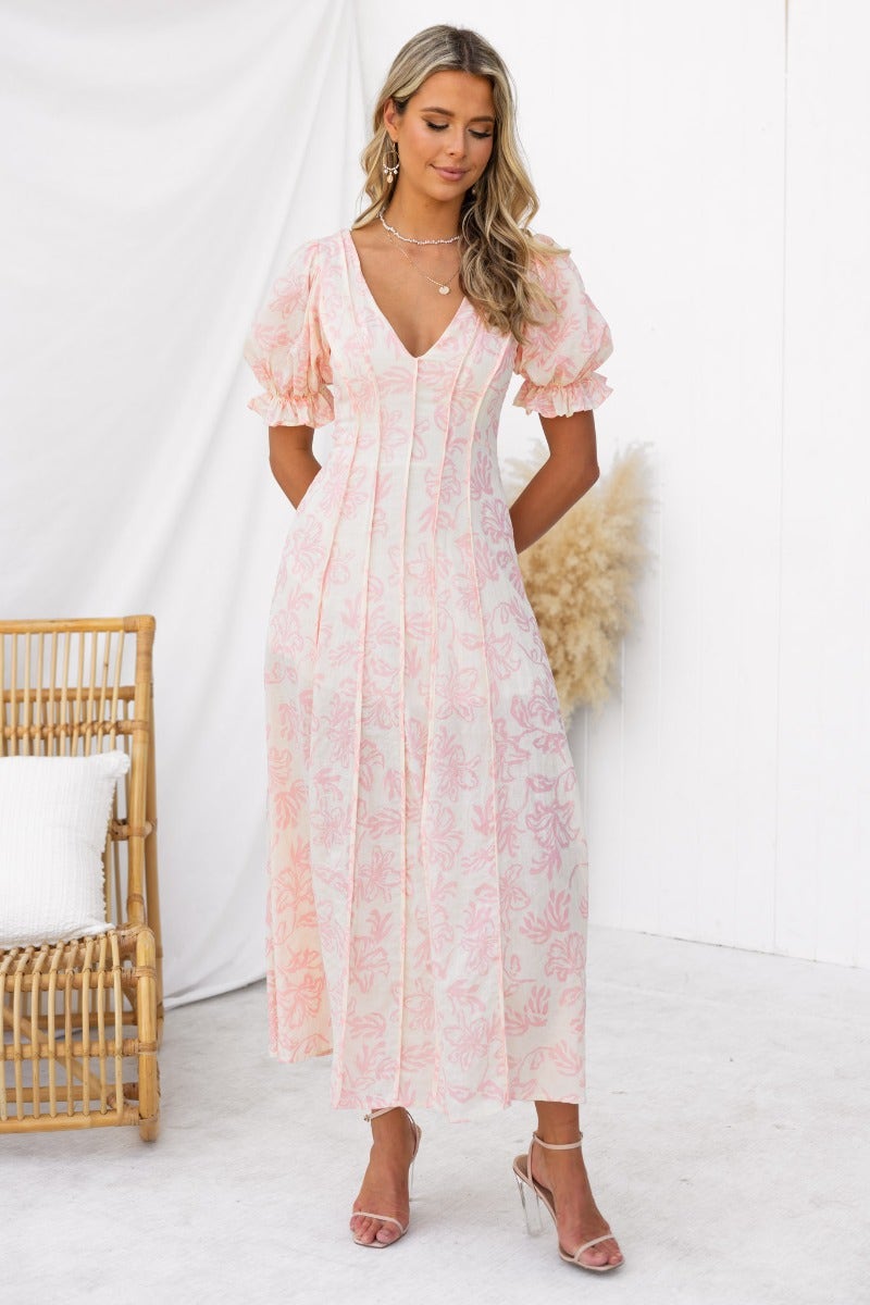 Adaline Maxi Dress featuring floral print, V-neckline, and elastic sleeves worn by a model in a bright setting.
