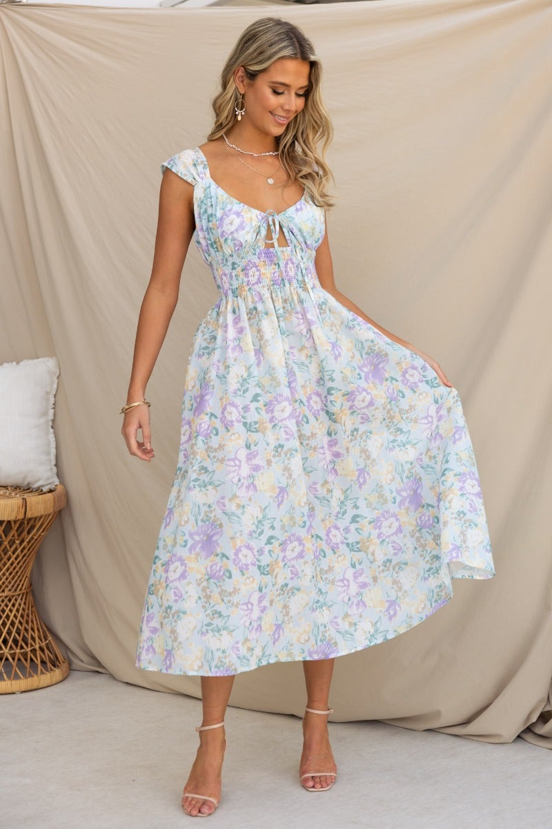 Sweet Nothing Midi Dress featuring floral print, tie detail at bust, and an elastic waistband in a stylish summer ensemble.
