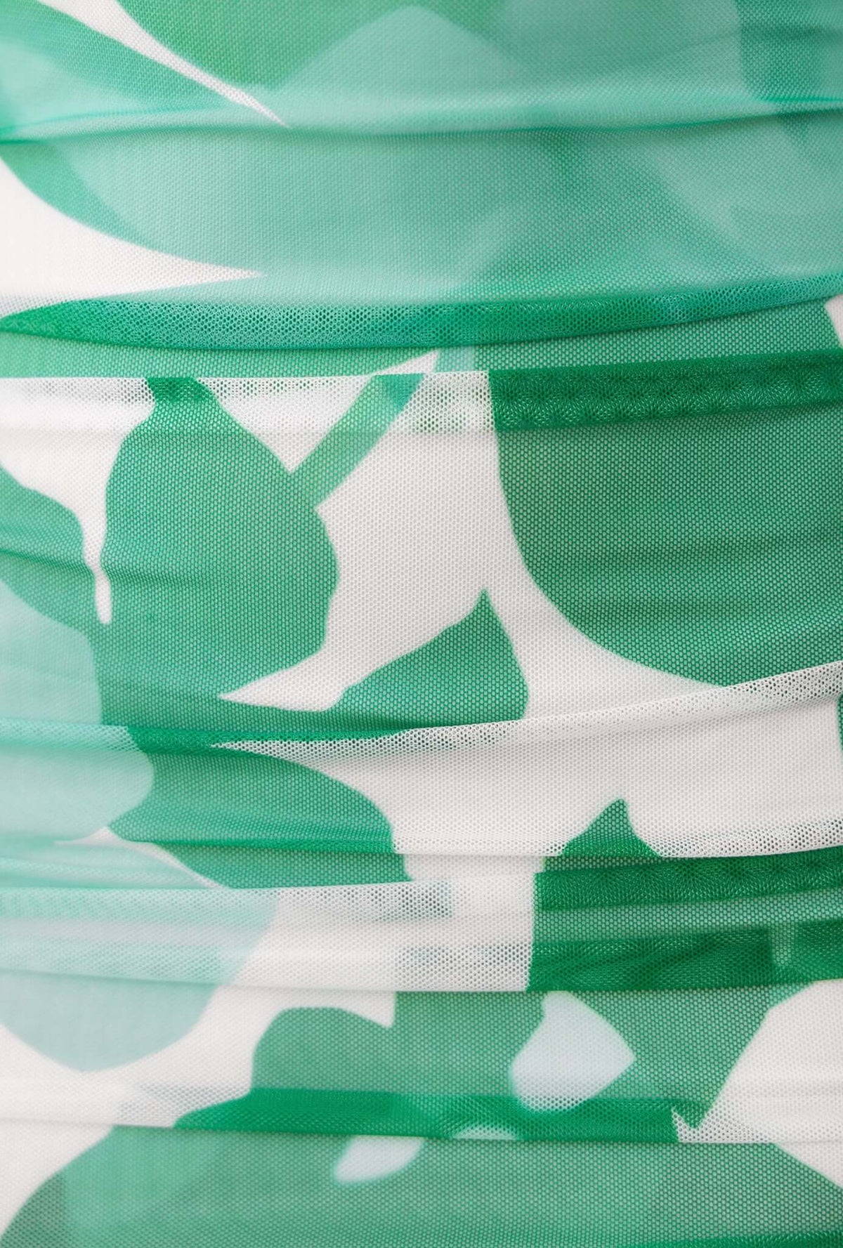 Close-up of green and white mesh fabric with leaf pattern, showcasing texture and stretch of material for an Oaklyn Maxi Dress.