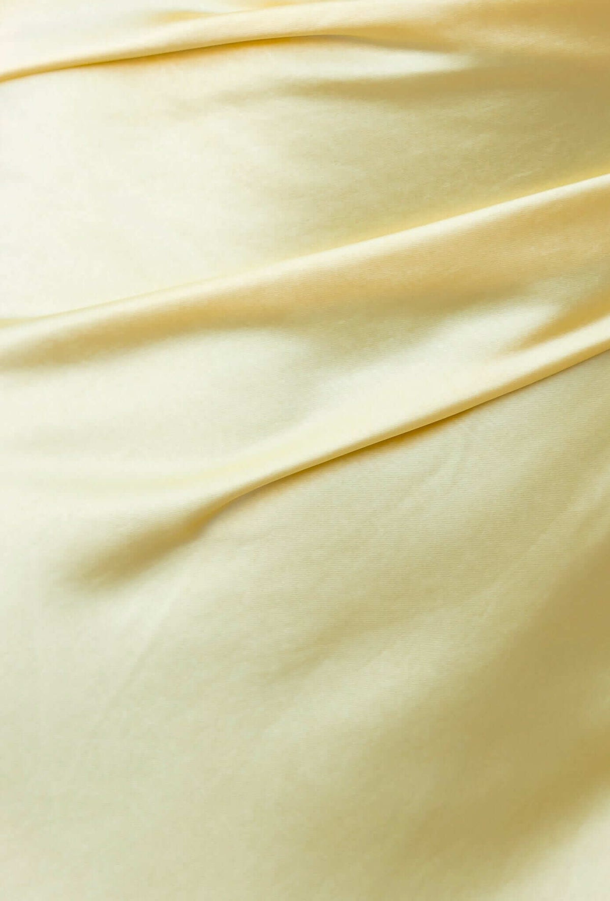 Close-up of the satin feel fabric in a soft yellow shade, showcasing a smooth, draped texture.