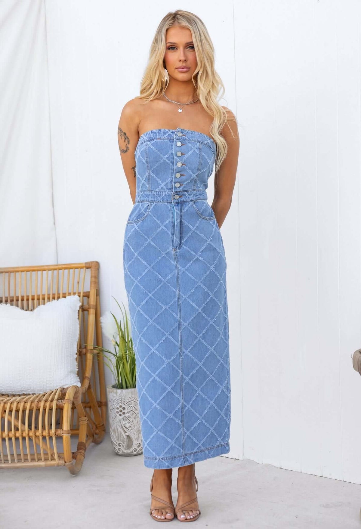 Strapless denim maxi dress with buttons, pockets, and back split, featuring a stylish fit on a model.
