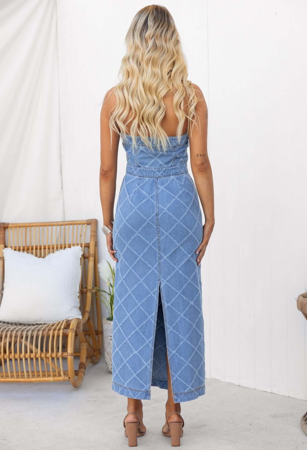 Back view of a woman in a strapless denim maxi dress with a split and pockets, showcasing a stylish summer look.