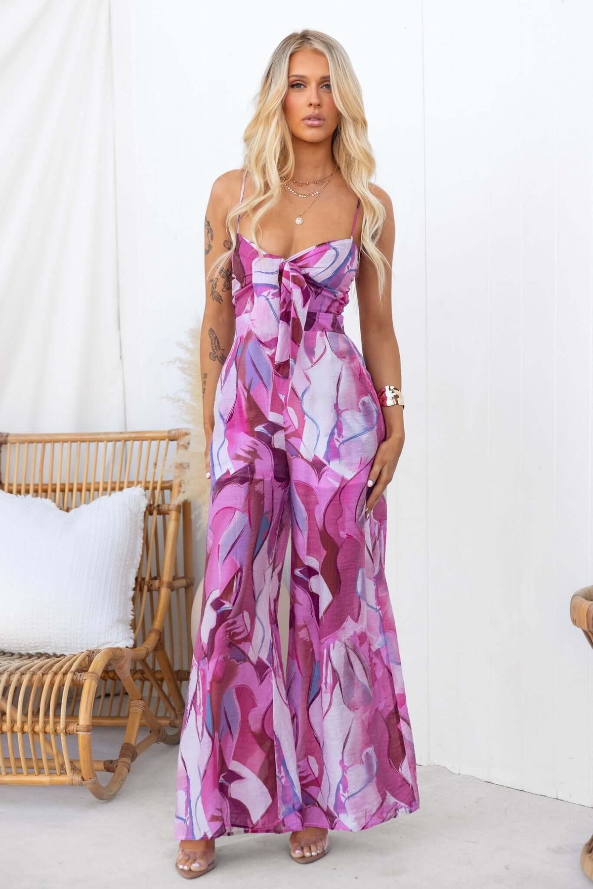 Model wearing a multi-colour Sun Dazed jumpsuit with adjustable straps and tie at bust, showcasing a stylish summer look.