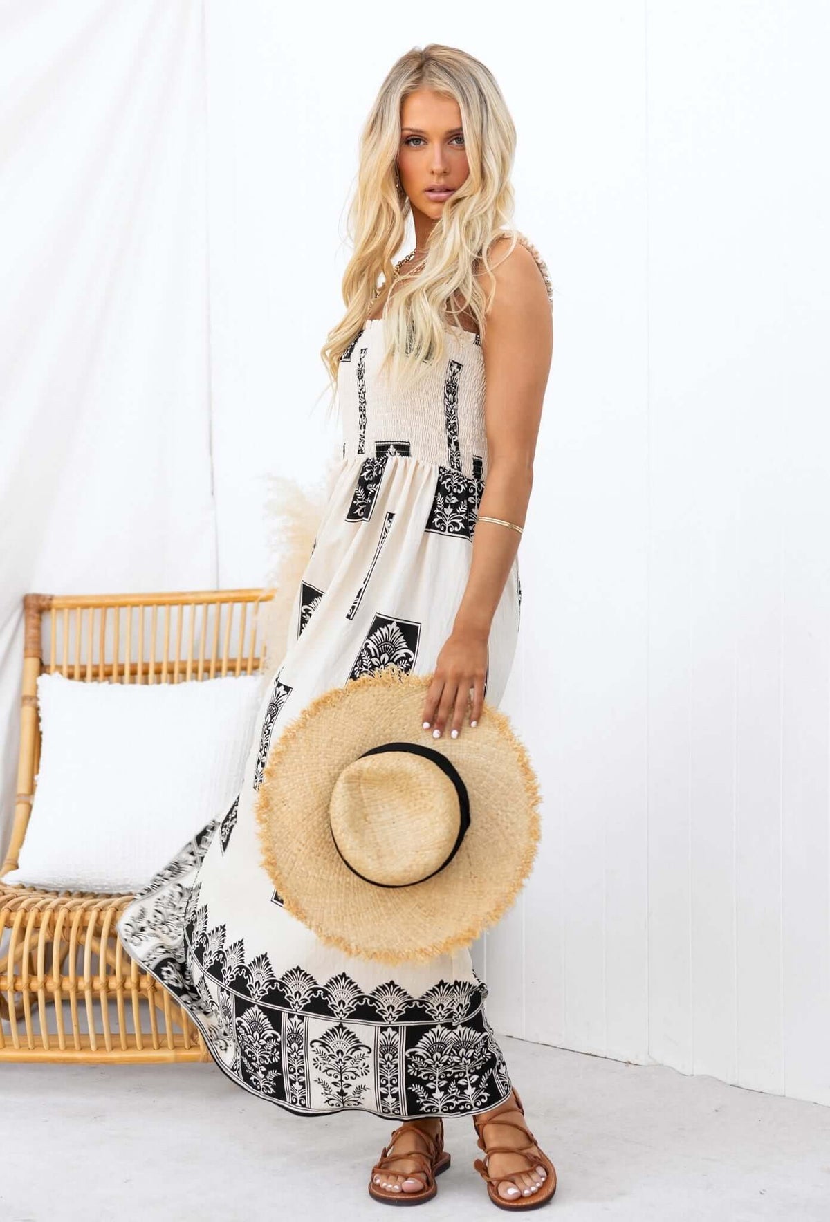 Model in Summer Fields Maxi Dress with black and white patterns, holding a straw hat, against a white background.