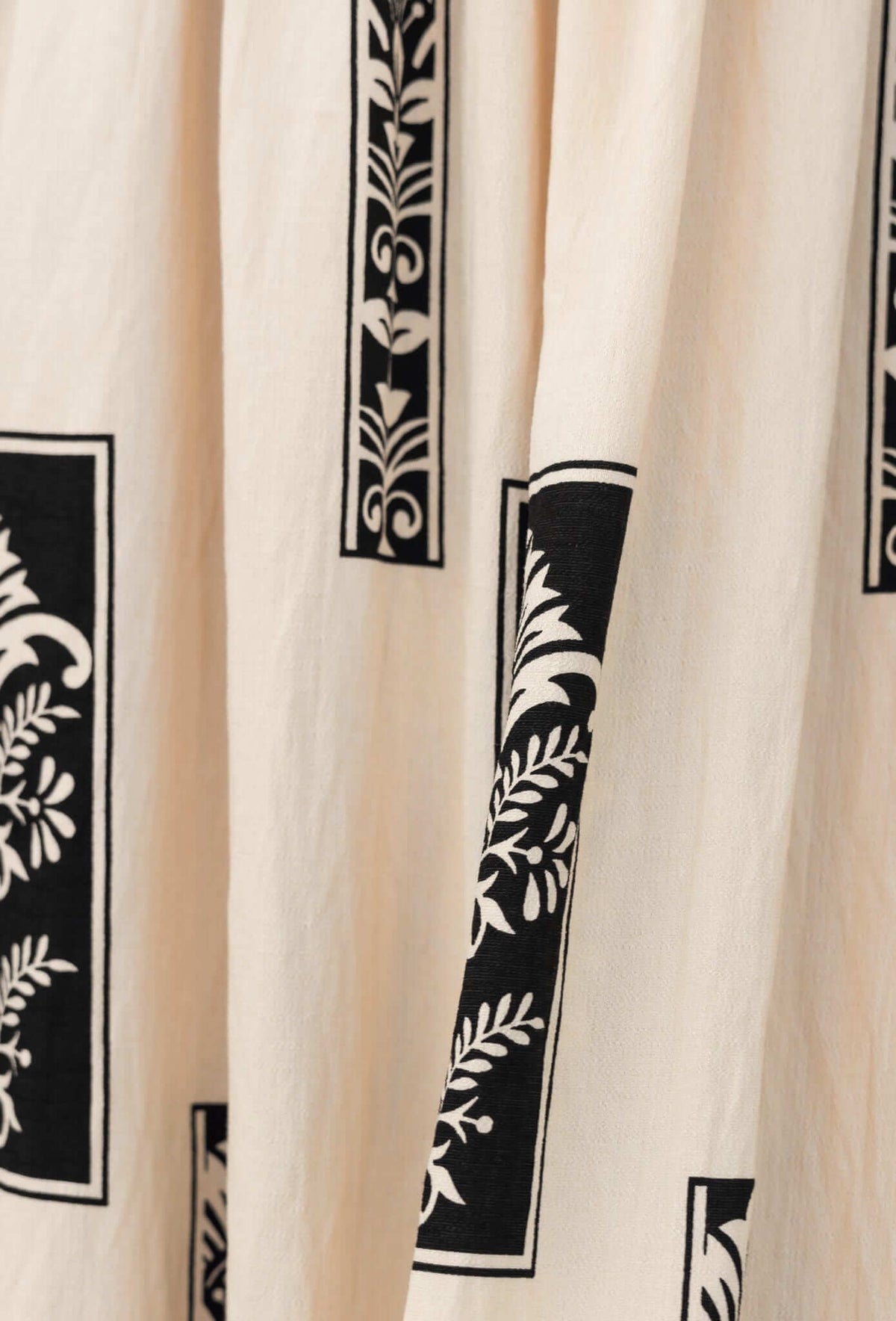 Detail of Summer Fields Maxi Dress fabric showing black floral and geometric pattern on light beige background.