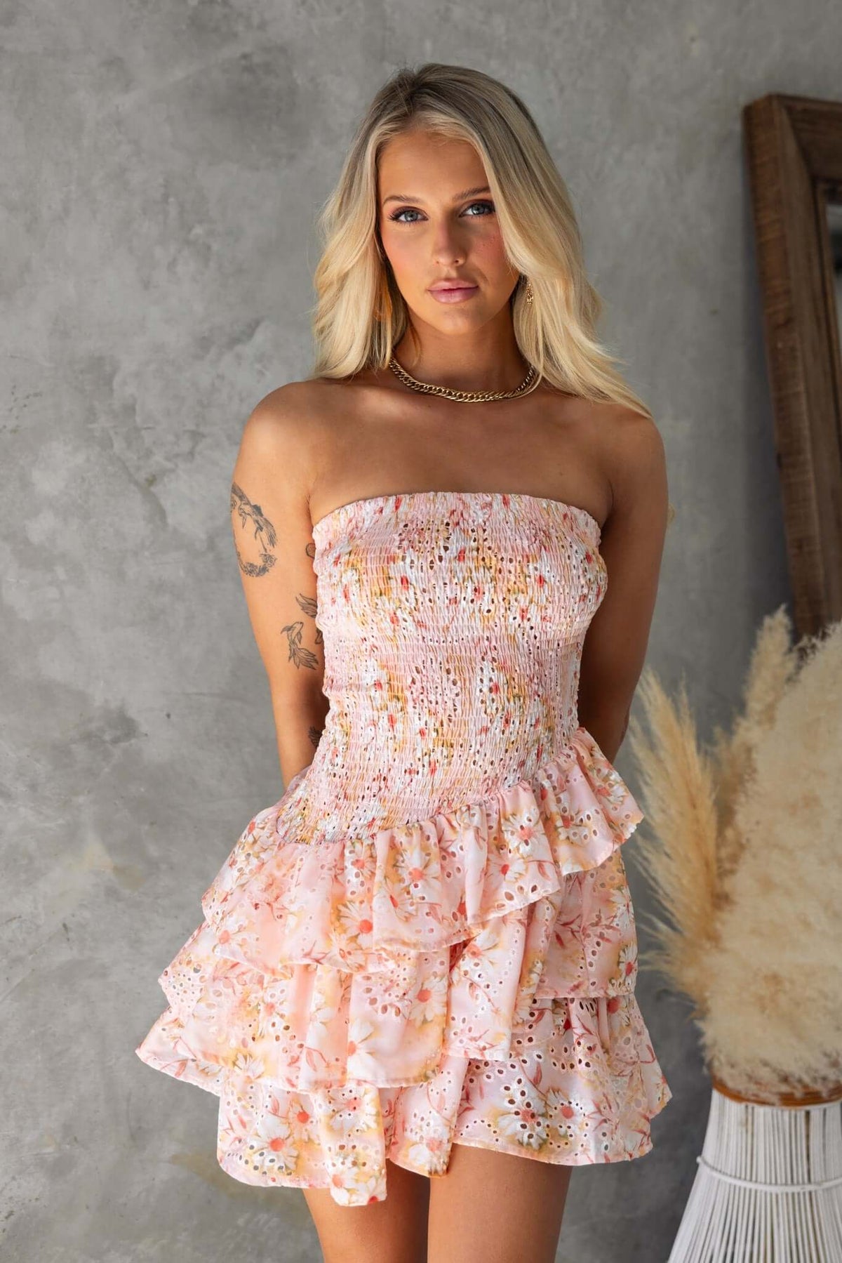 Model wearing Tiny Dancer Mini Dress, a pink strapless dress with shirred bodice and ruffle hem, perfect for summer.