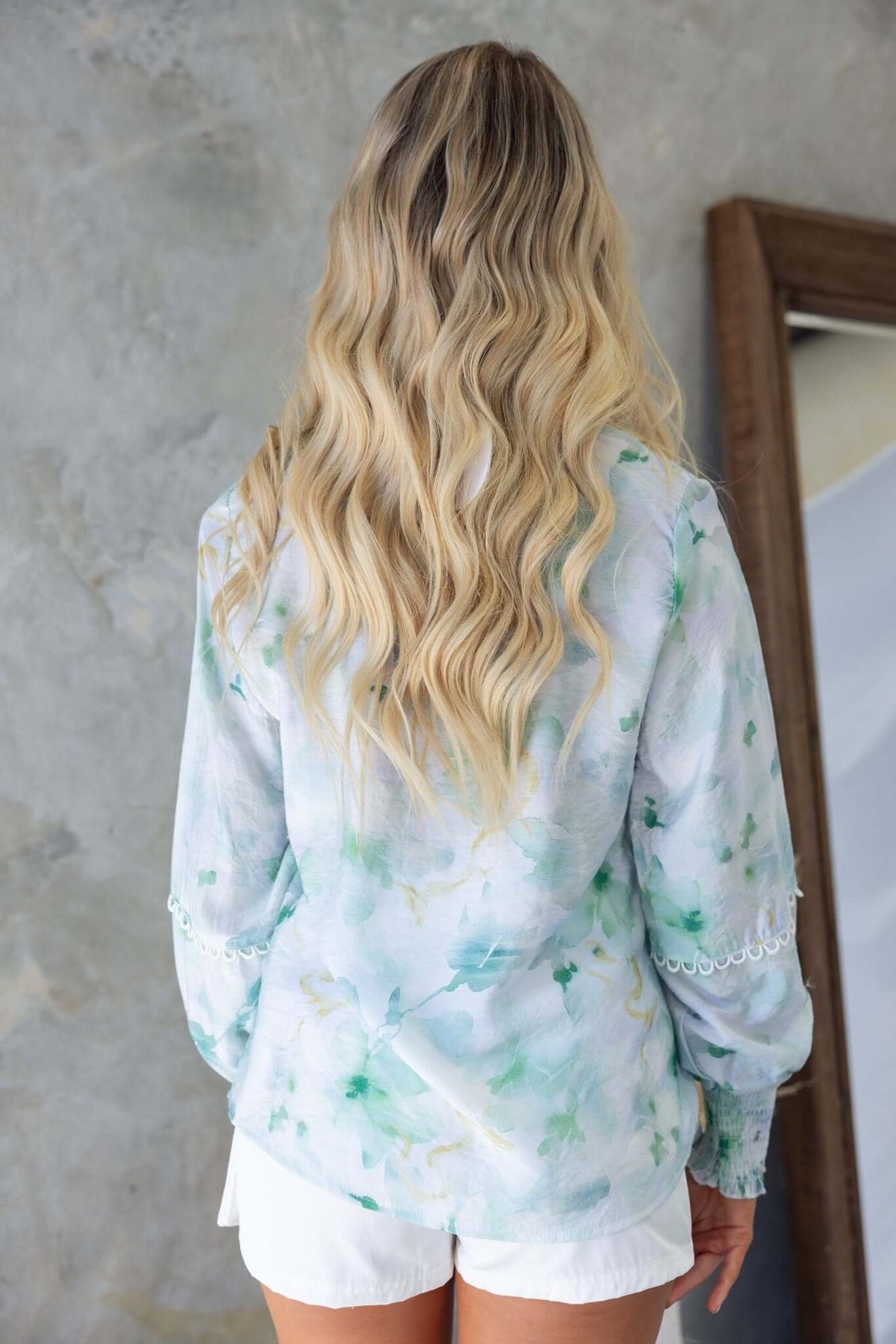 Back view of a woman wearing the Kellee Shirt, showcasing its floral design and elastic sleeves.