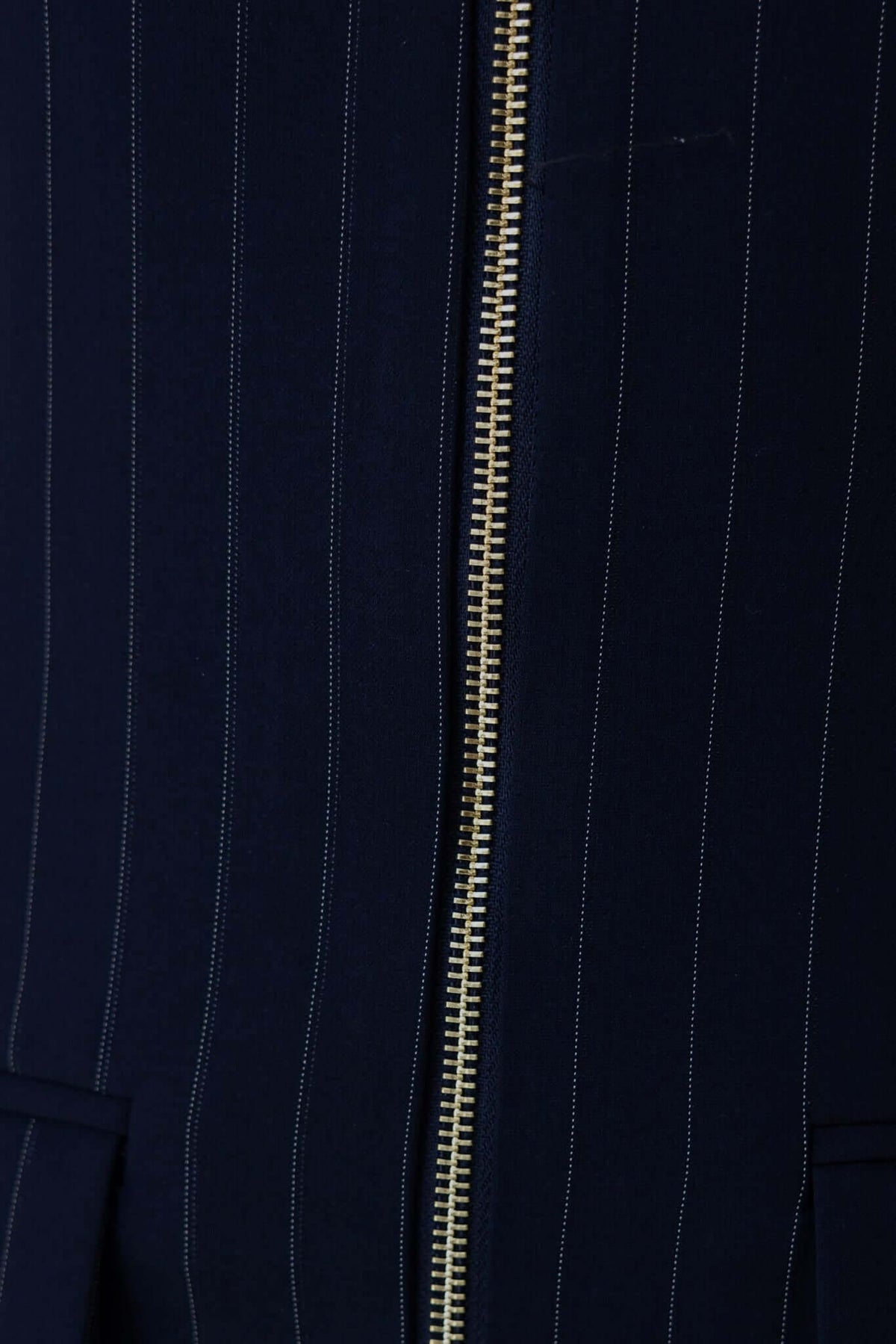 Close-up of Catie Dress featuring dark navy fabric, gold zip front, and subtle pinstripes.