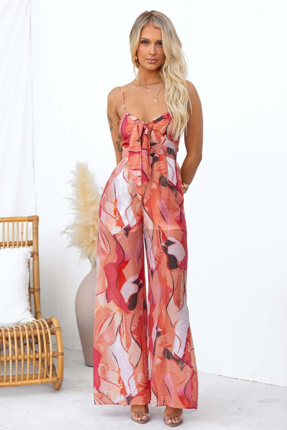 Sun Dazed Jumpsuit features a colorful print, adjustable straps, tie detail, and pockets, perfect for stylish summer outings.