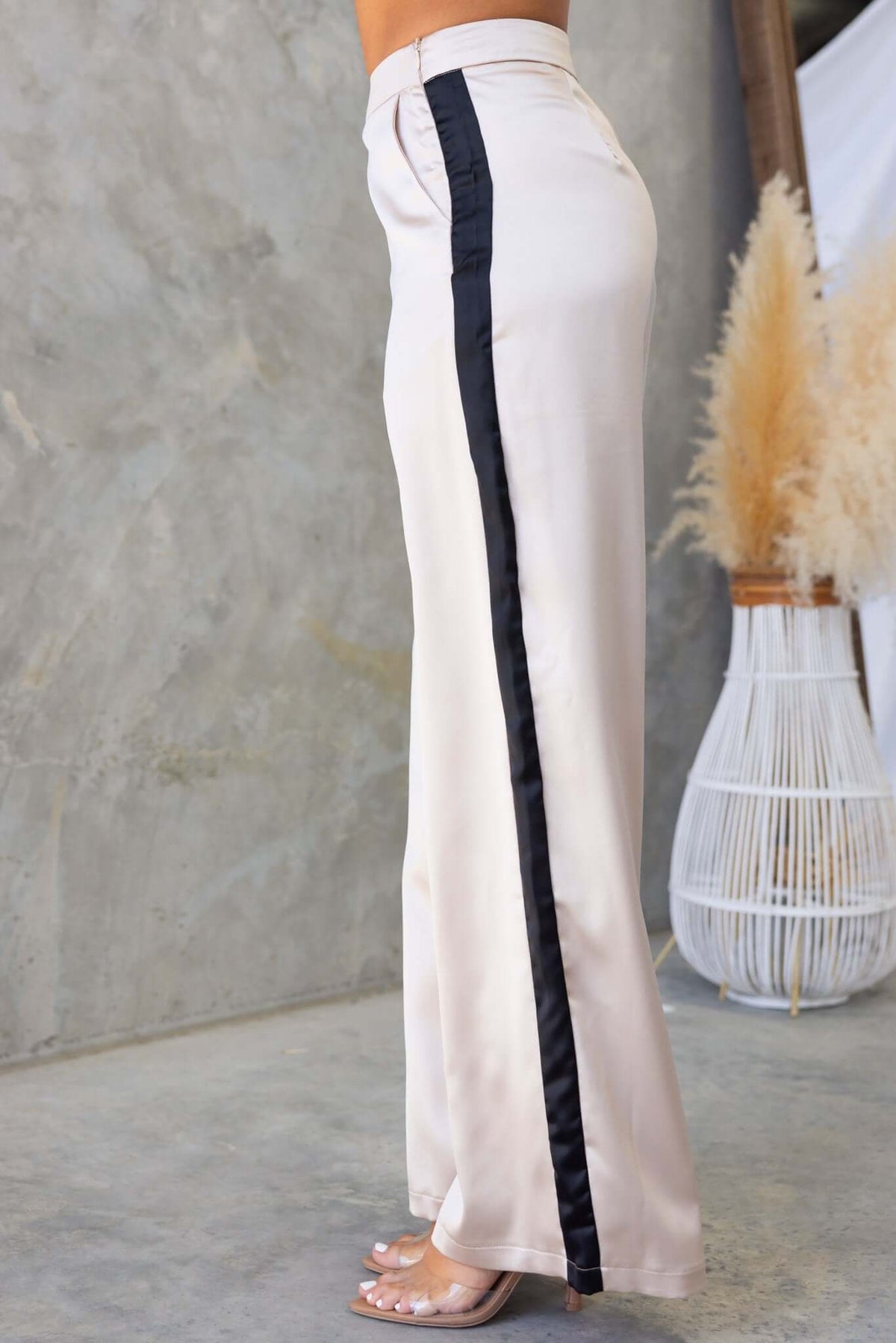 Tanaya Pants in cream with satin finish, featuring a mid-high waist and side pockets, styled with a black side stripe.