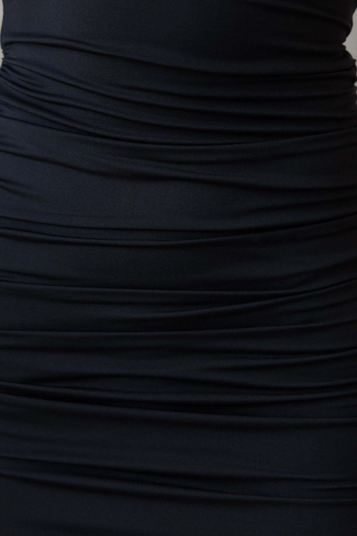 Close-up of the textured, ruched black fabric of the Esha Maxi Dress showcasing its elegant design.