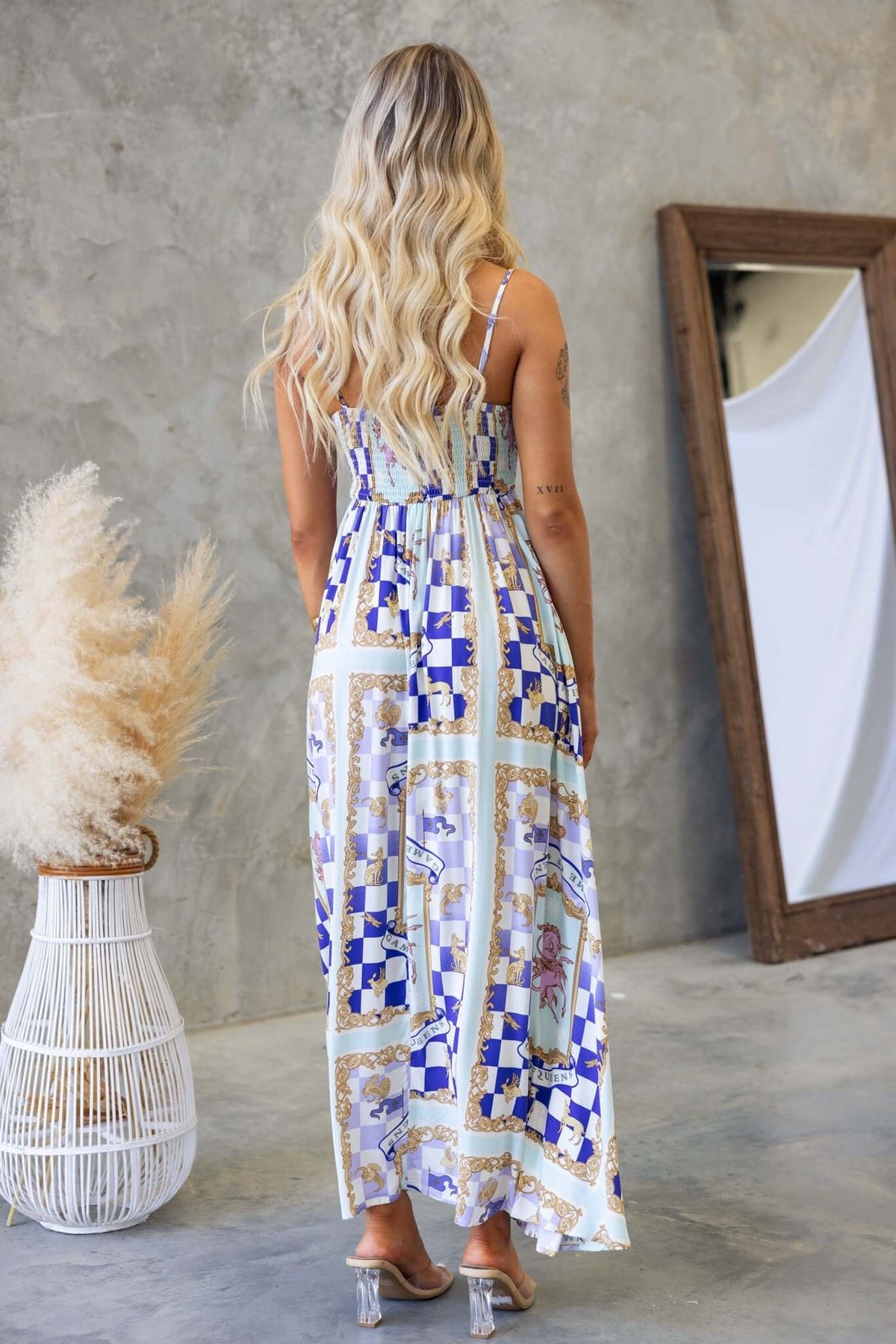 Back view of a woman in a stylish Salilah Maxi Dress with adjustable straps and colorful print, showcasing a modern design.