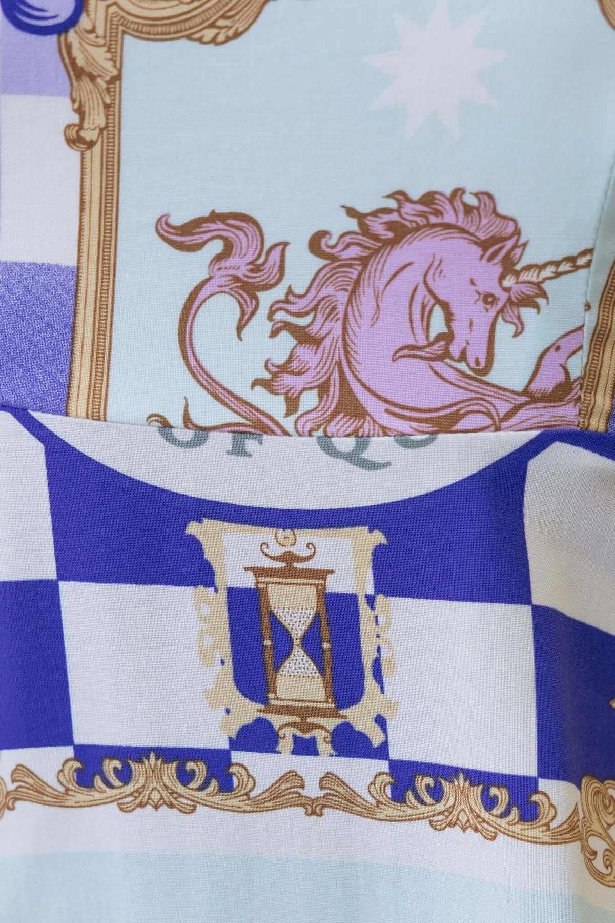 Close-up of Salilah Maxi Dress fabric featuring whimsical unicorn and decorative patterns in blue and gold.