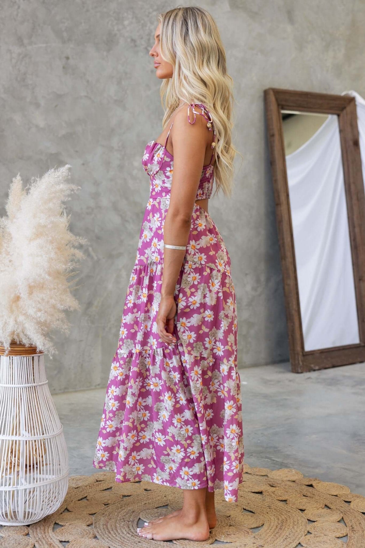 Side view of a model wearing a Daring Midi Dress with tie straps and floral print, set in a stylish interior.