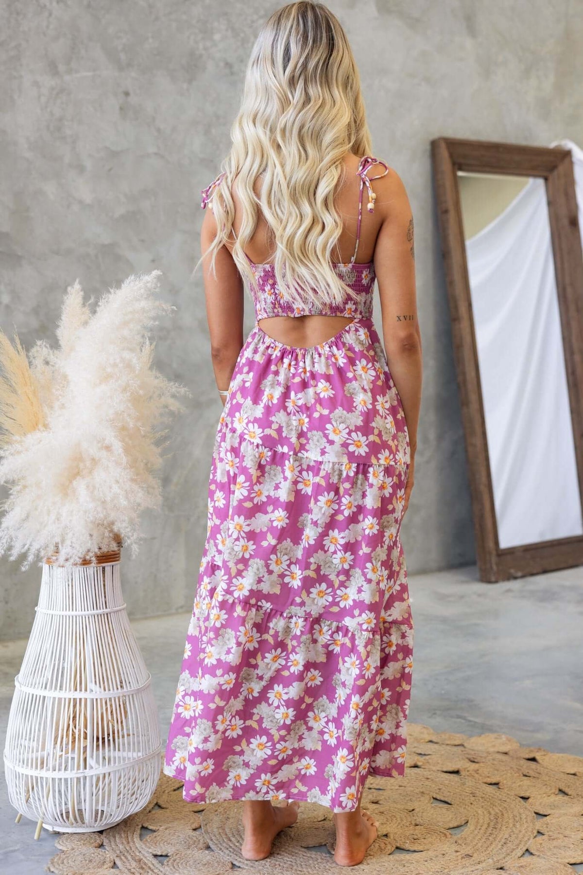 Back view of a woman in a floral Daring Midi Dress with tie straps and a cut-out, showcasing a stylish bohemian look.