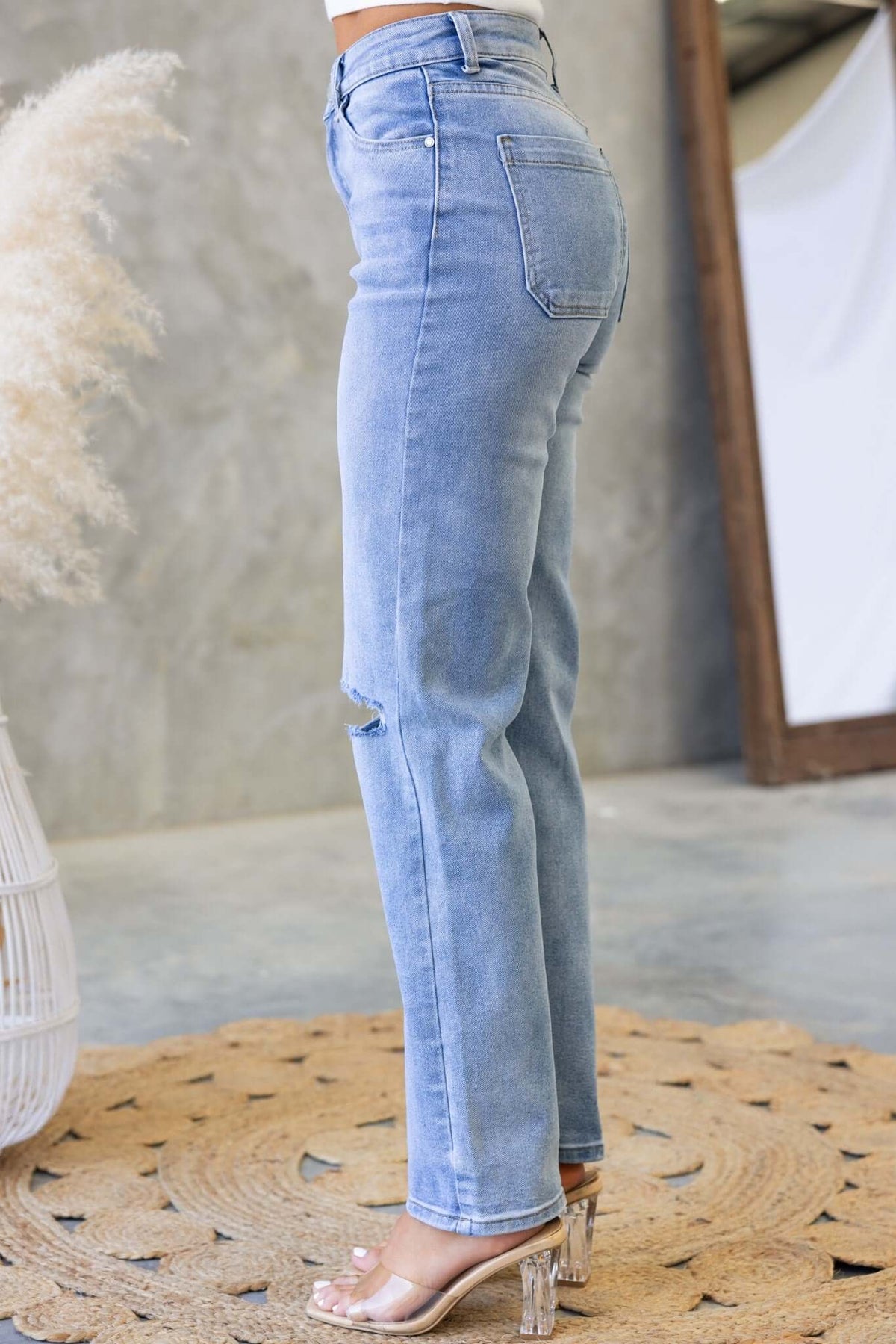 Side view of Tekin distressed denim jeans, showcasing rips and a slim fit against a stylish background.