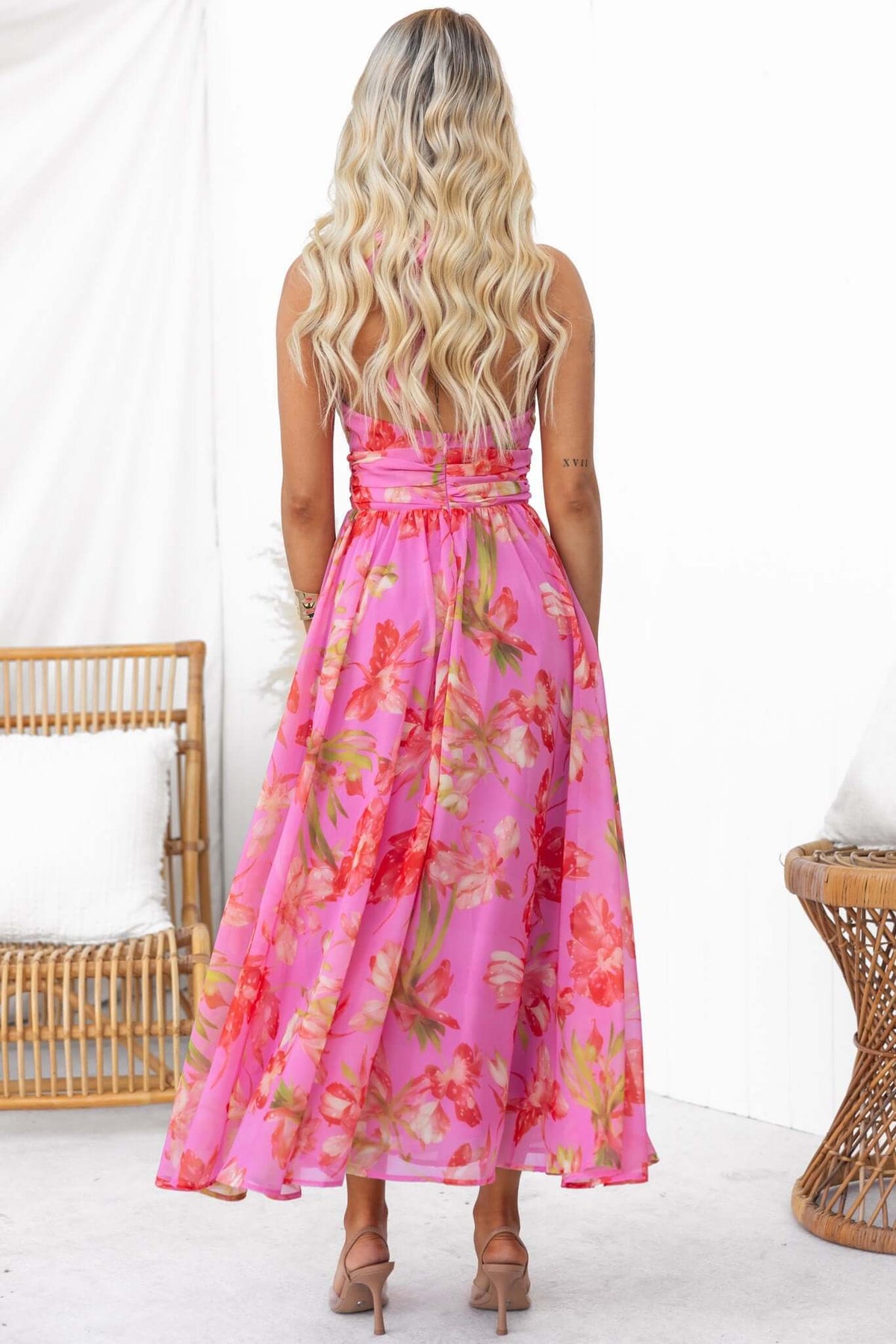 Woman wearing a pink floral Giulianna Maxi Dress with tied neck and zip back, showcasing the back view.