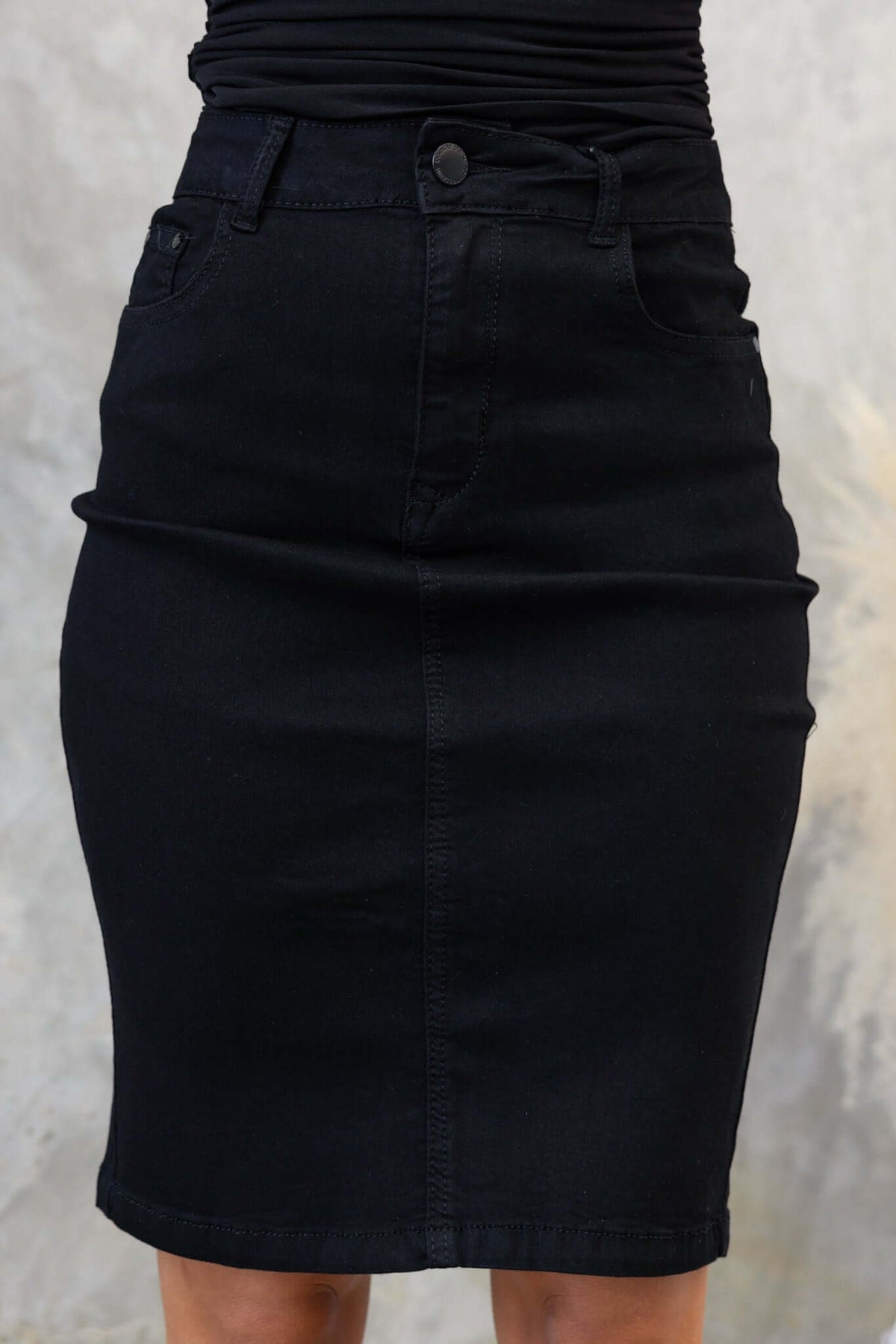 Black mid-high waist denim skirt with pockets and back split, showcasing a firm stretch fit.