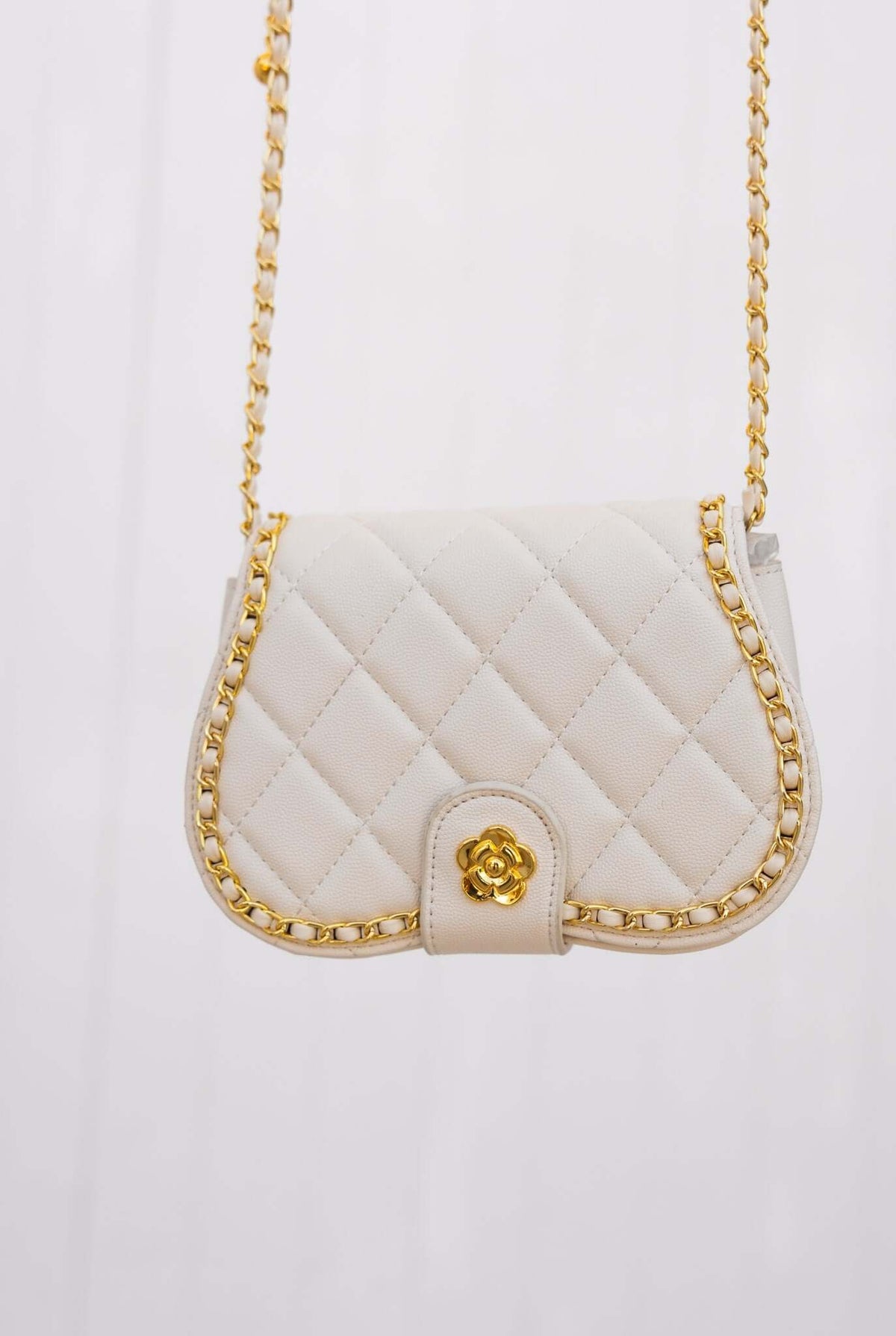 Chic white quilted handbag with gold chain strap and decorative flower clasp.