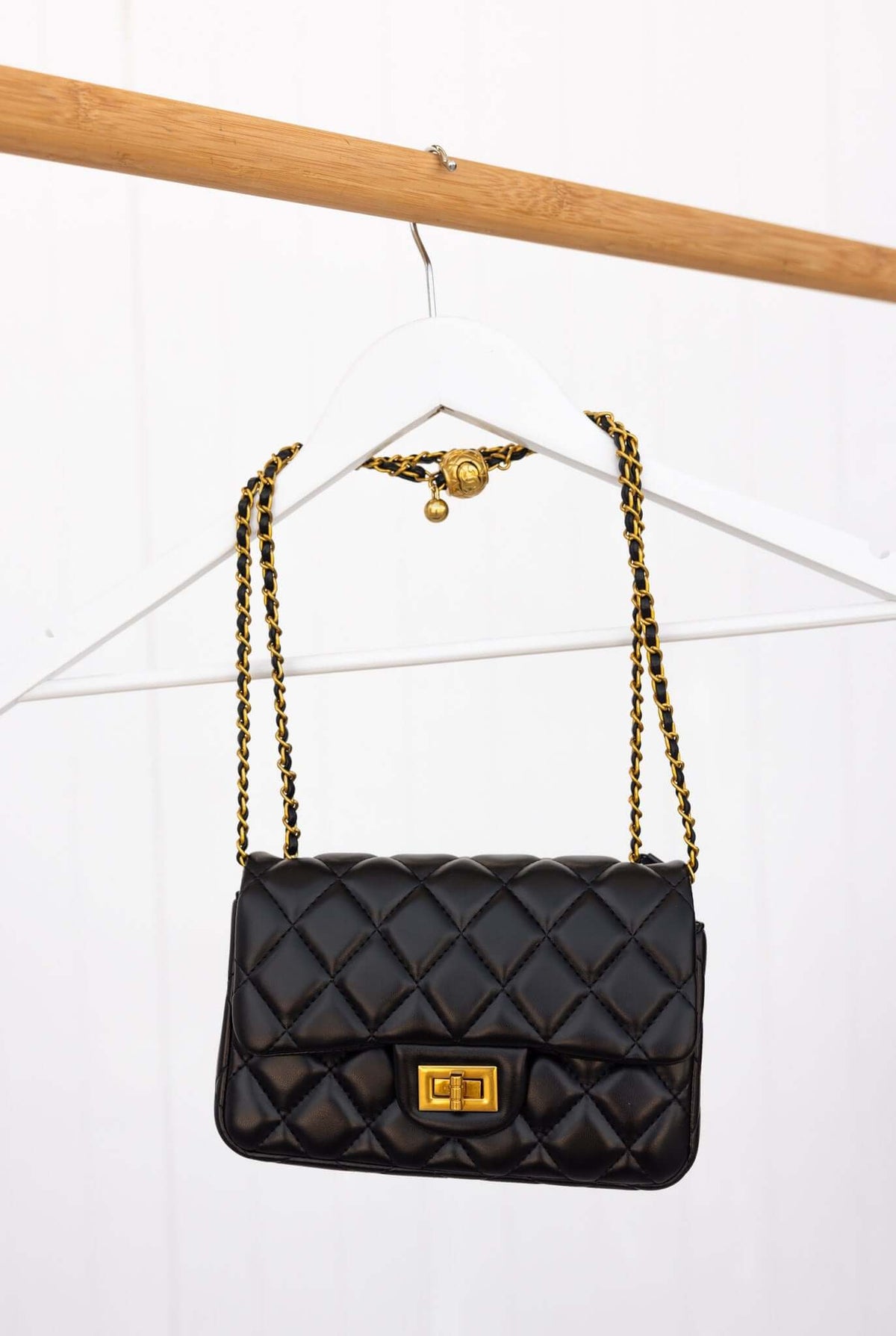 Chic quilted black Chelsea bag with gold hardware, featured on a hanger, perfect for stylish nights out.