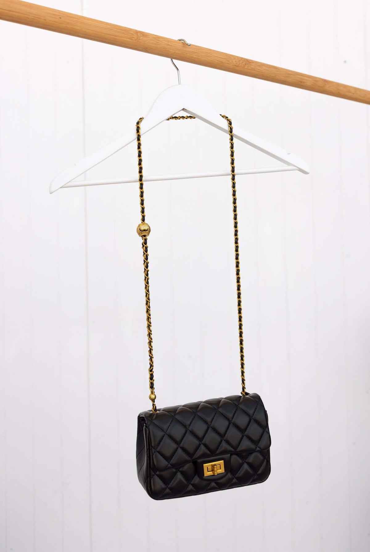 Chic Chelsea Bag with quilted finish and gold hardware, stylishly hanging on a wooden hanger.