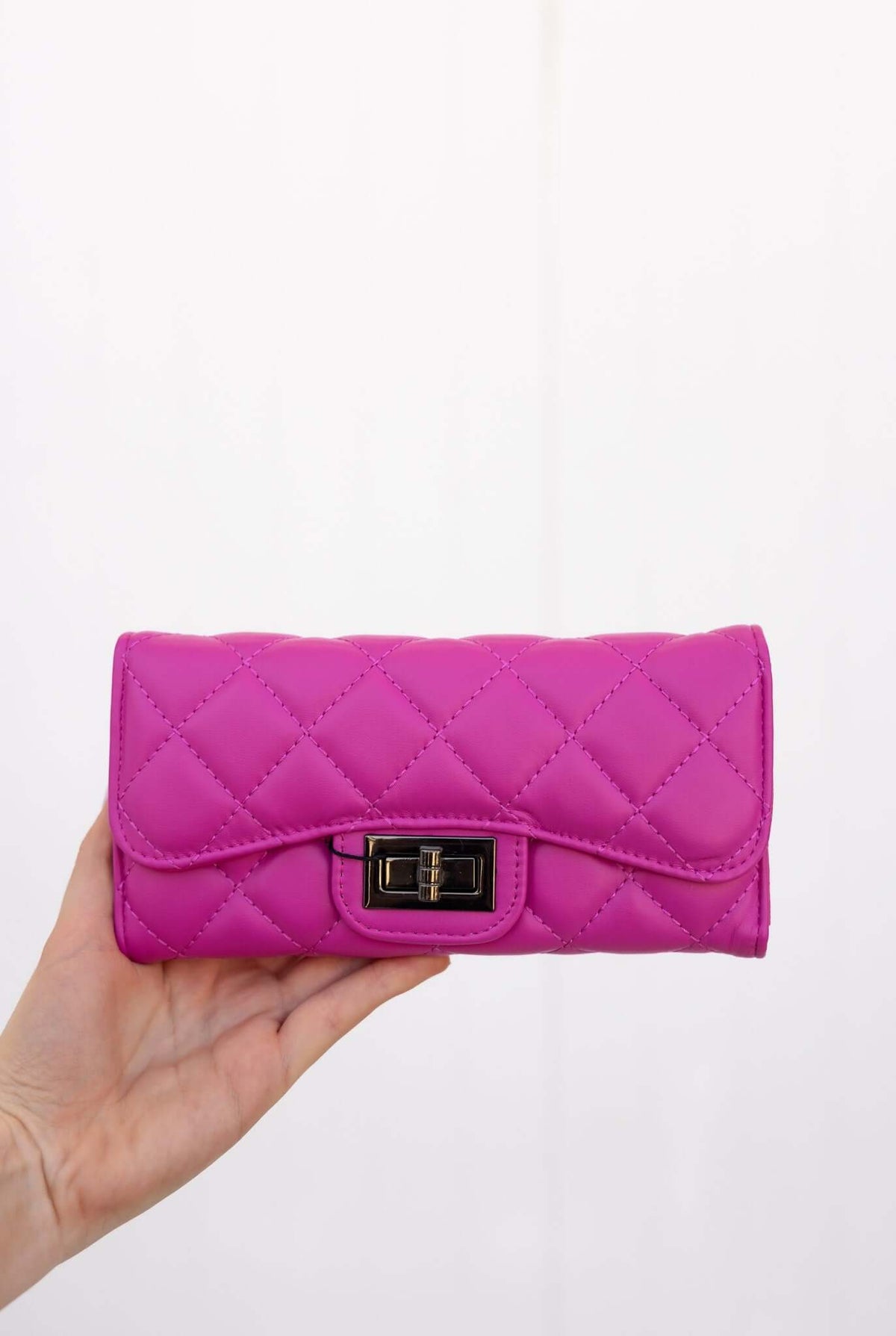 Asta Wallet in vibrant pink vegan leather with quilted design and clasp, featuring compartments and card slots.