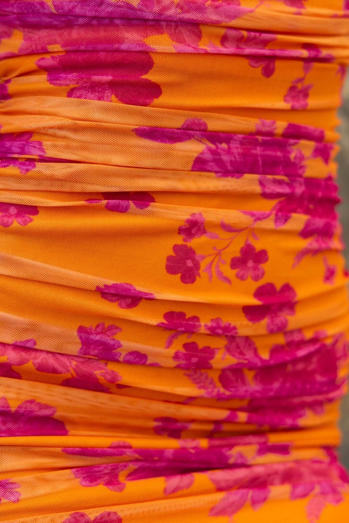Close-up of Azriel Midi Dress showcasing vibrant orange fabric with pink floral patterns and ruched detailing.