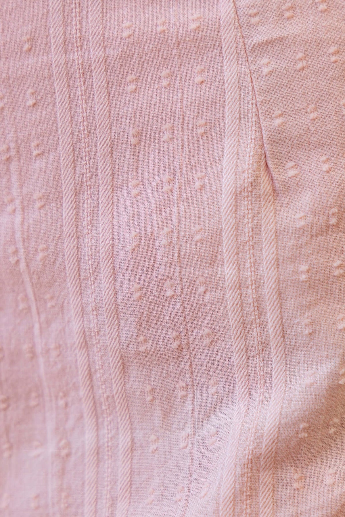 Close-up of textured pink fabric with subtle stripes and patterns, ideal for the Nove Skirt.
