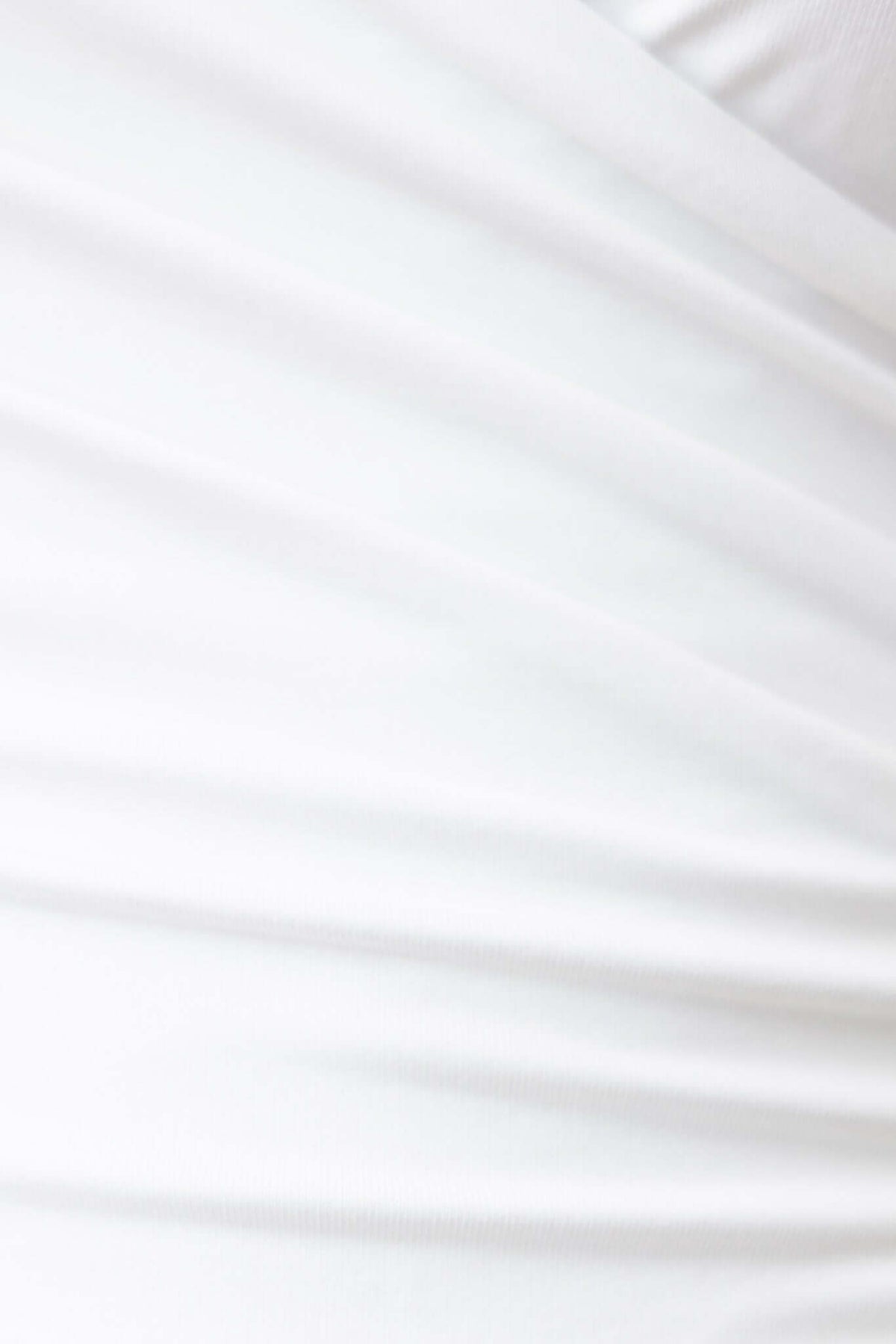 Close-up of soft, stretchy white fabric showing texture, ideal for Oskar Bodysuit with adjustable straps and V-neckline.