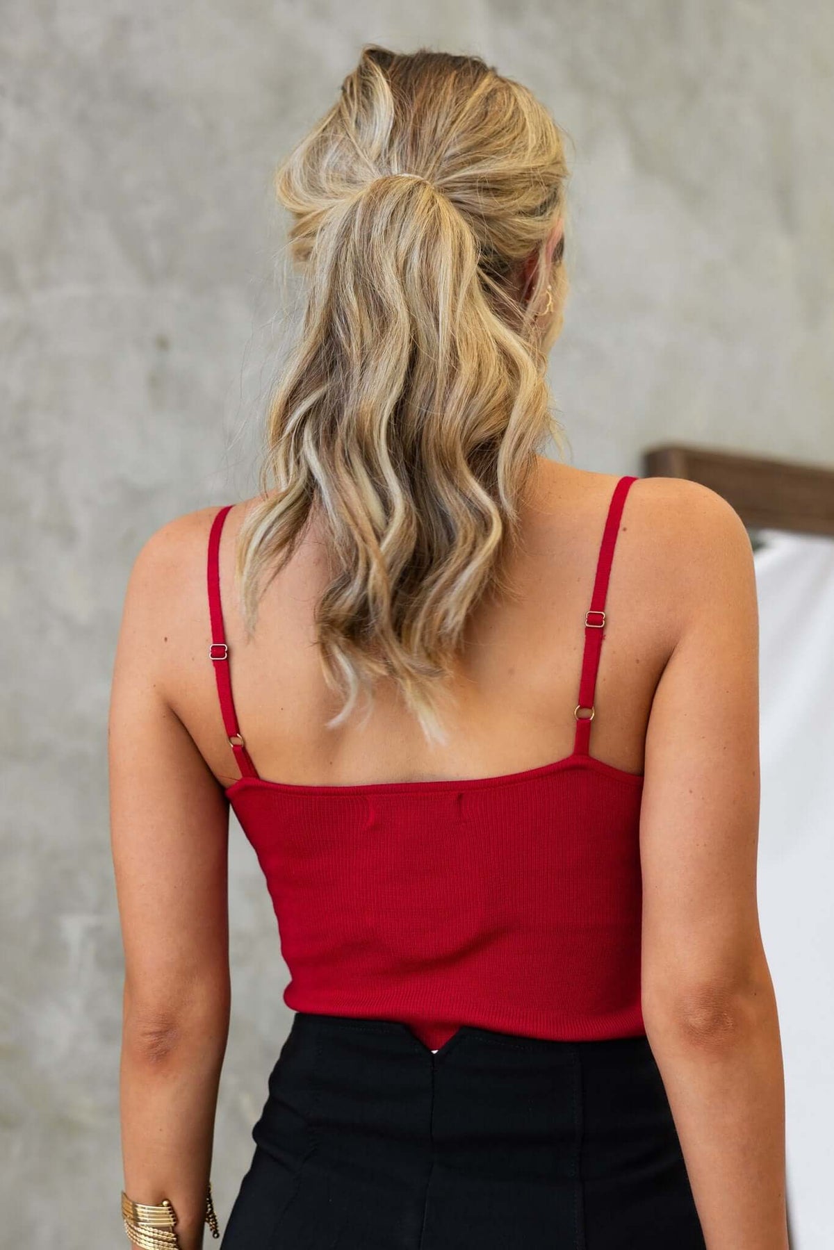 Back view of a woman wearing a red Imani Top with adjustable straps, showcasing a stylish, fitted design.
