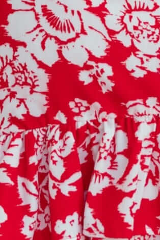 Red and white floral pattern fabric with ruffled detail, showcasing the Meriden Dress's vibrant design.