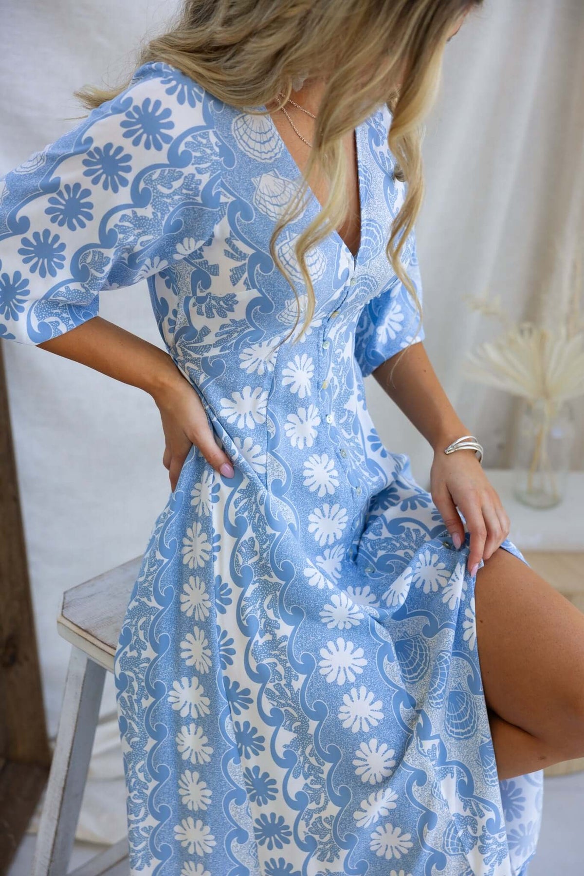 Model showcasing the Hartford Maxi Dress in blue floral print, featuring a V-neckline and button-up front.