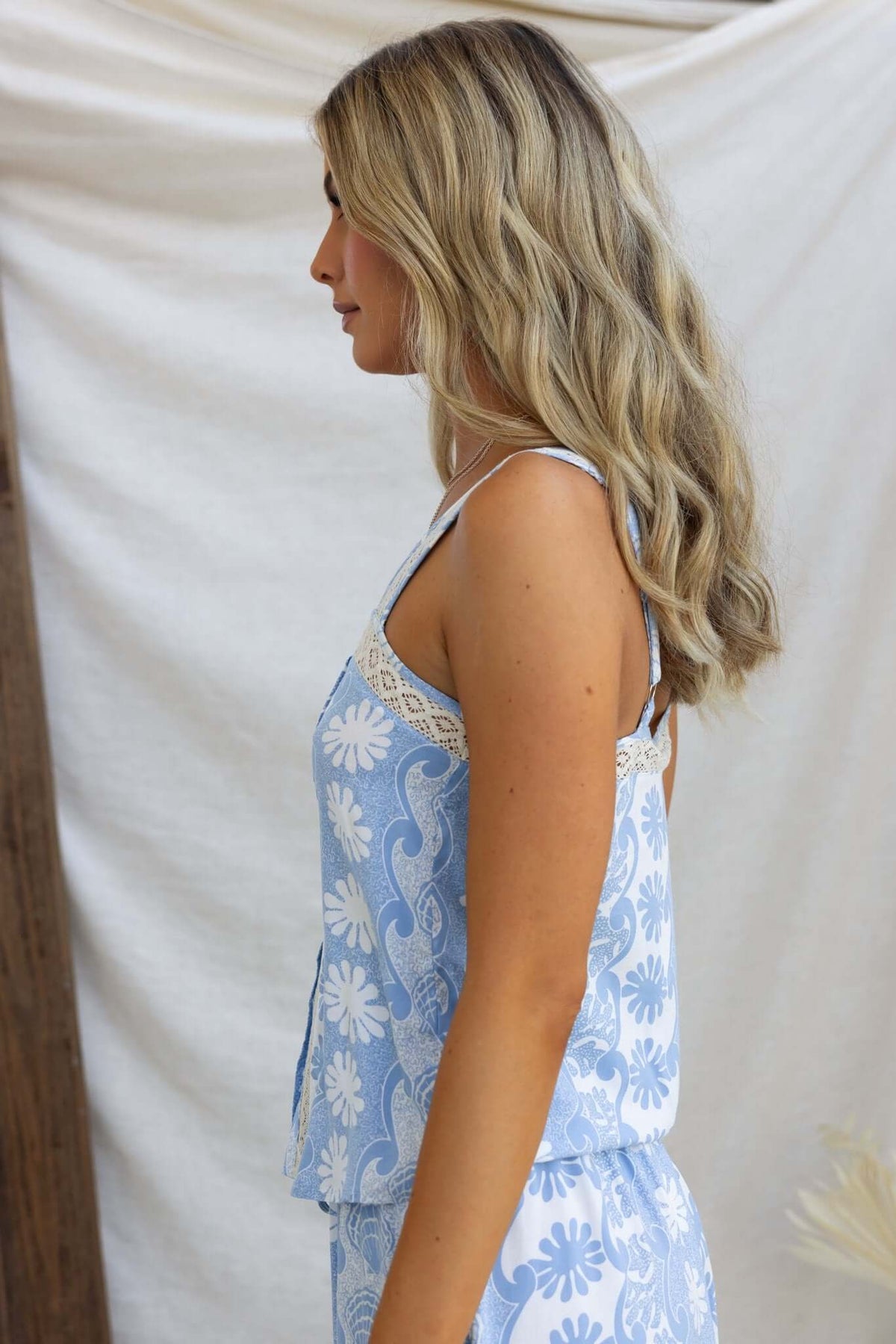 Lunita Top in blue floral print featuring adjustable straps and a button-up front, modeled by a woman.