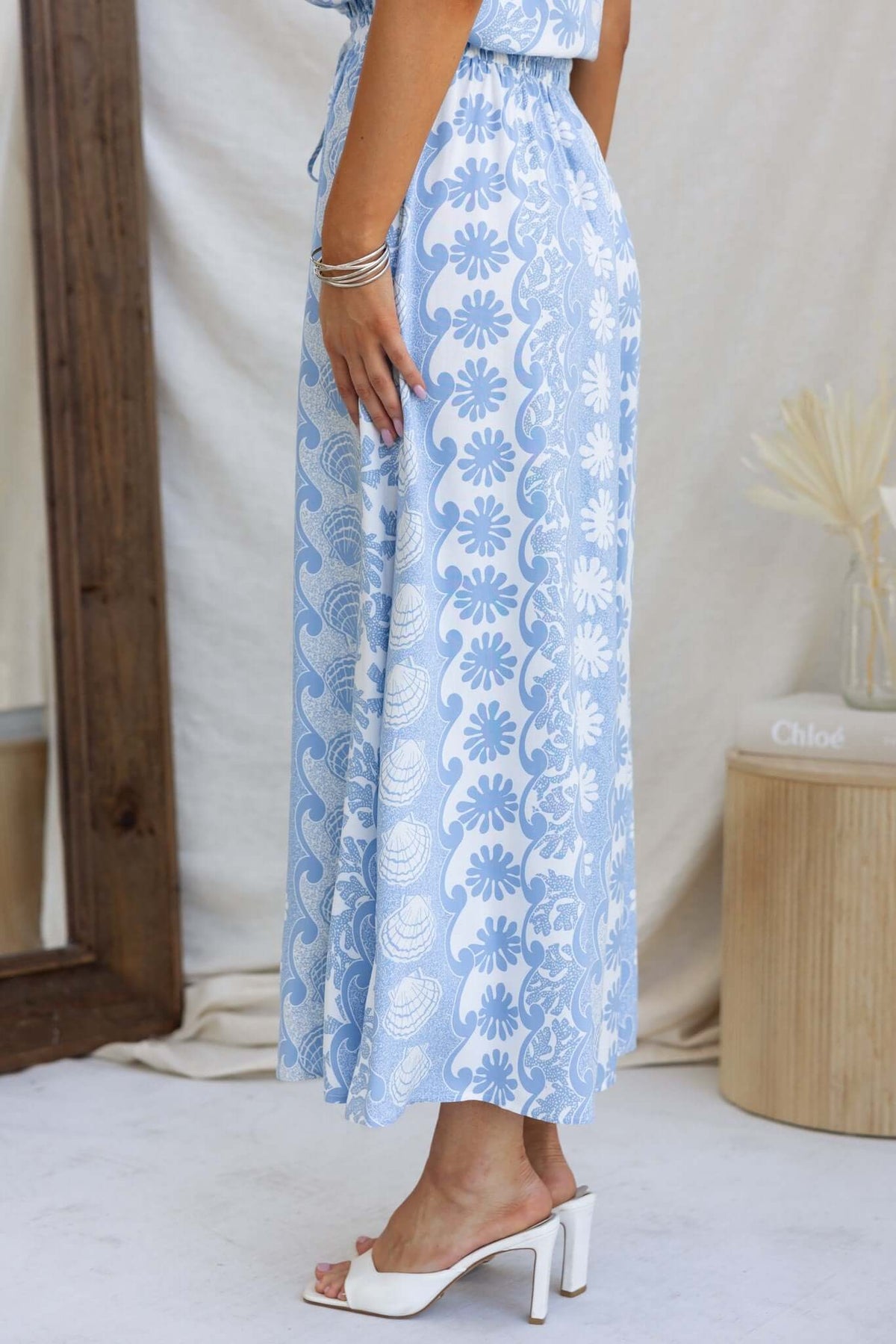 Side view of woman wearing Lunita Pants with floral pattern in blue, showcasing mid-high waist and pockets.