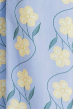 Detail of light blue fabric featuring yellow flowers and green leaves, perfect for a spring or summer maxi dress.