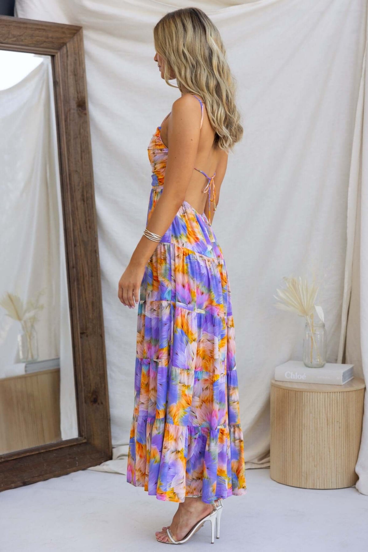Side view of Emmelina Maxi Dress featuring floral patterns, adjustable straps, and a tied back design.