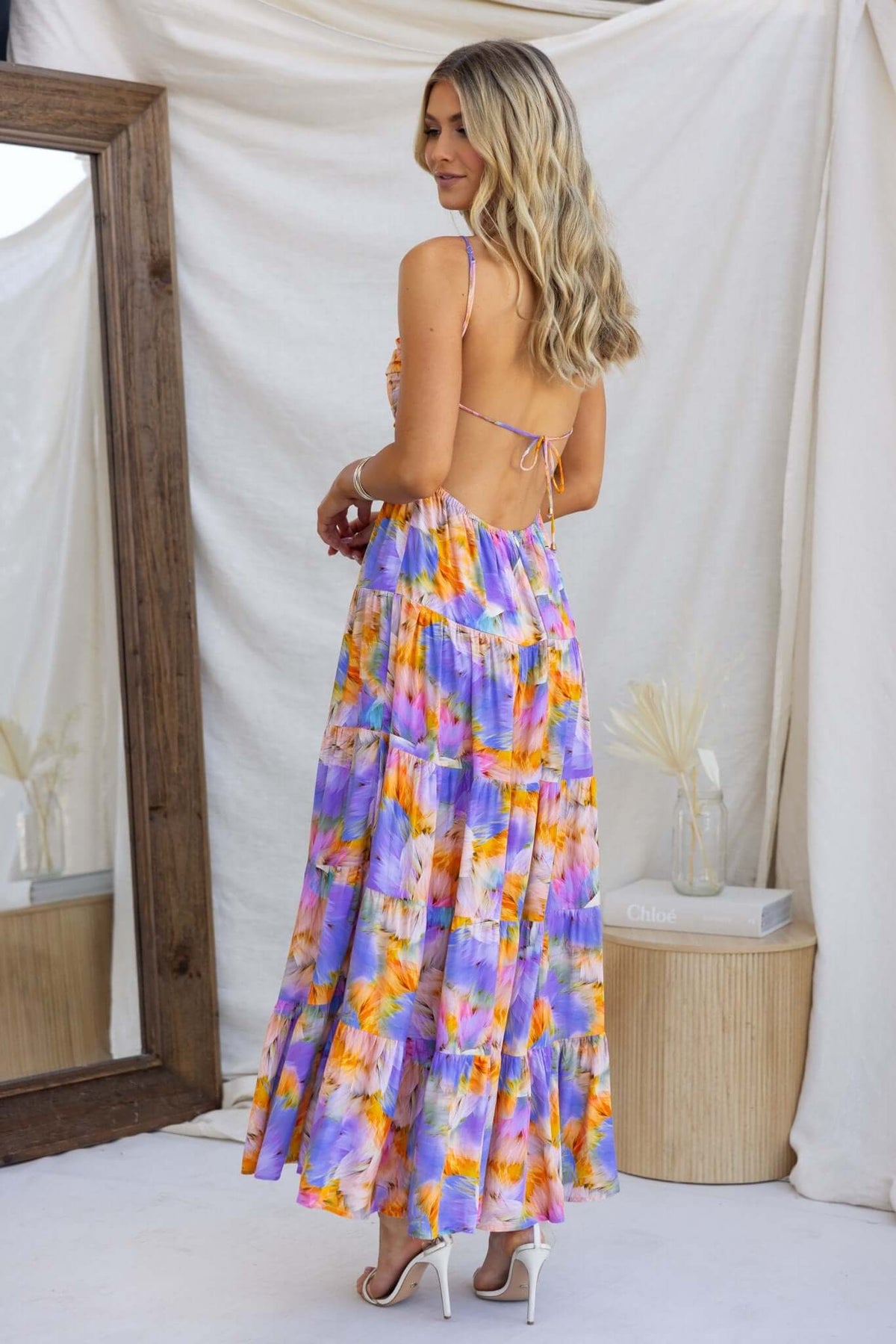 Model wearing Emmelina Maxi Dress with adjustable straps and a colorful floral pattern, showcasing the back design.