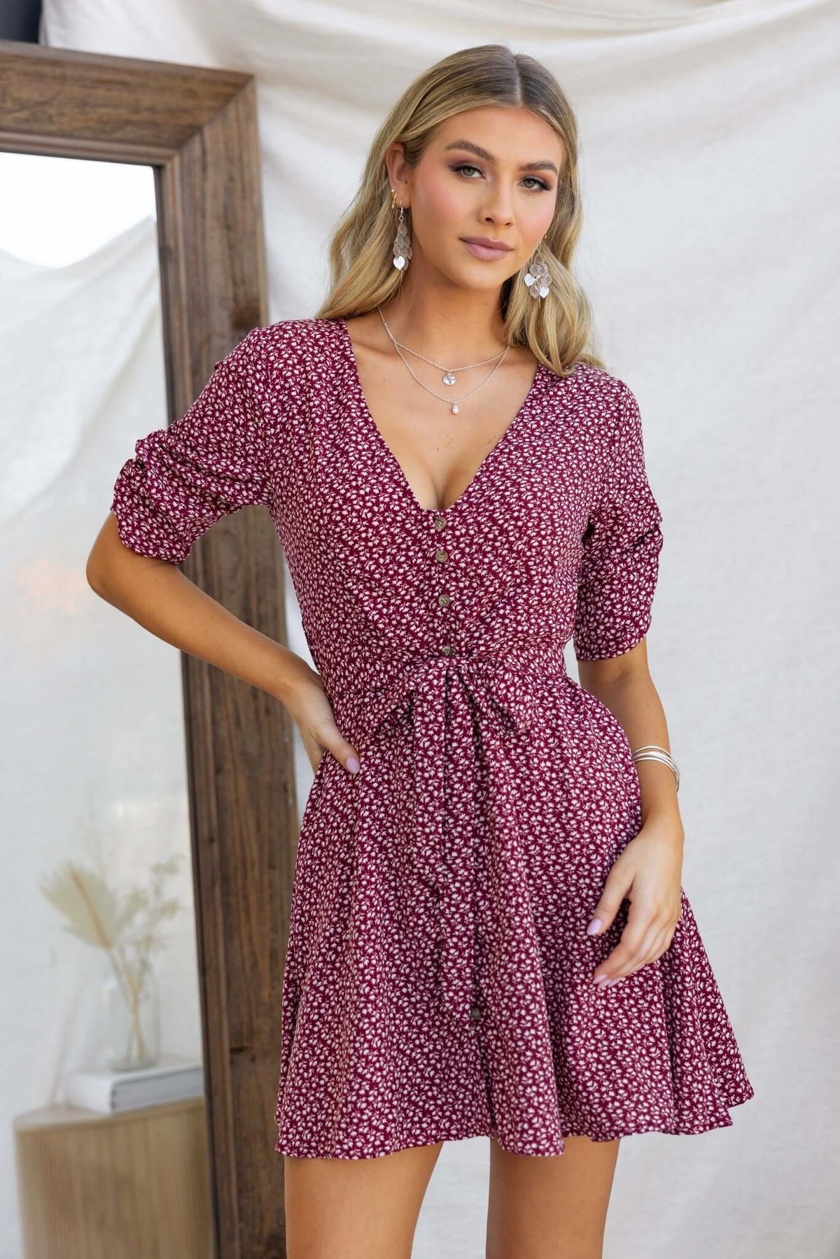 Farsan dress featuring a V-neckline, button-up front, and removable tie, worn by a model in a stylish setting.