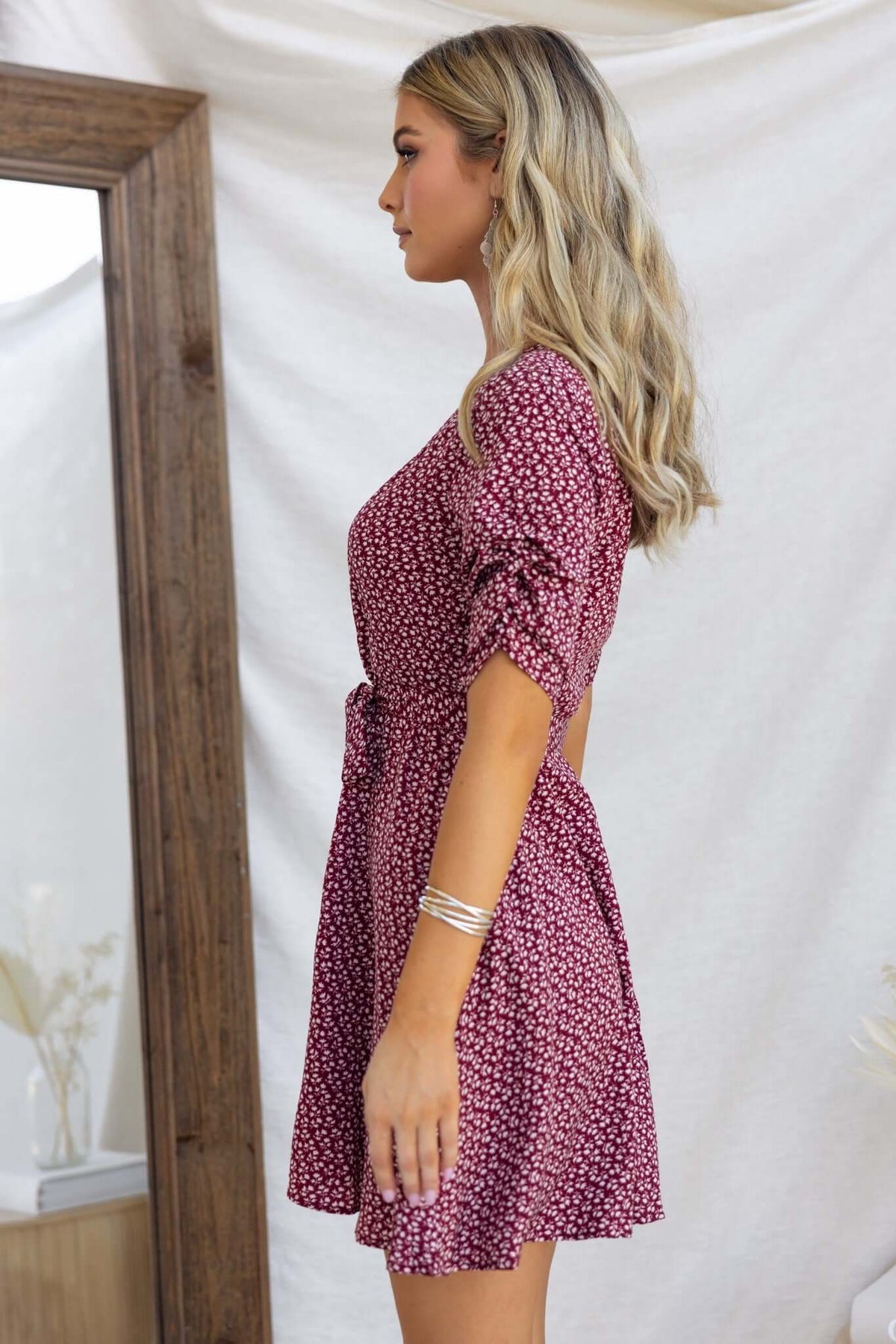 Farsan Dress featuring a V-neckline, button-up front, and elastic sleeves on a model in a stylish setting.