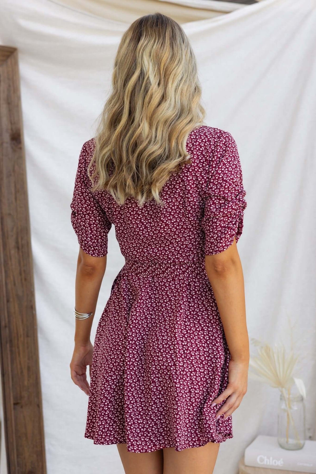 Back view of a woman in a floral Farsan dress with puff sleeves and a tie at the waist.