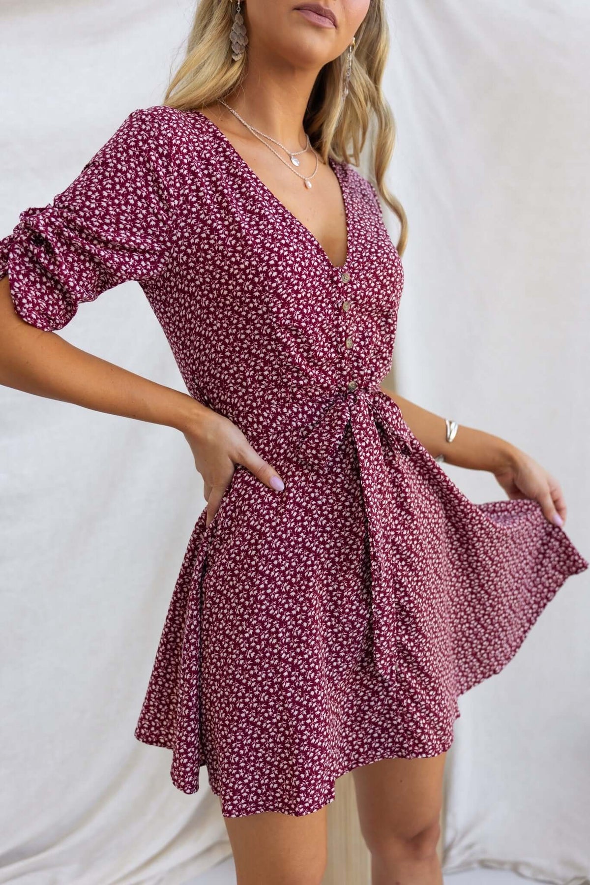 Model wearing a vibrant Farsan dress with a V-neckline, button-up front, and removable tie, showcasing floral pattern.