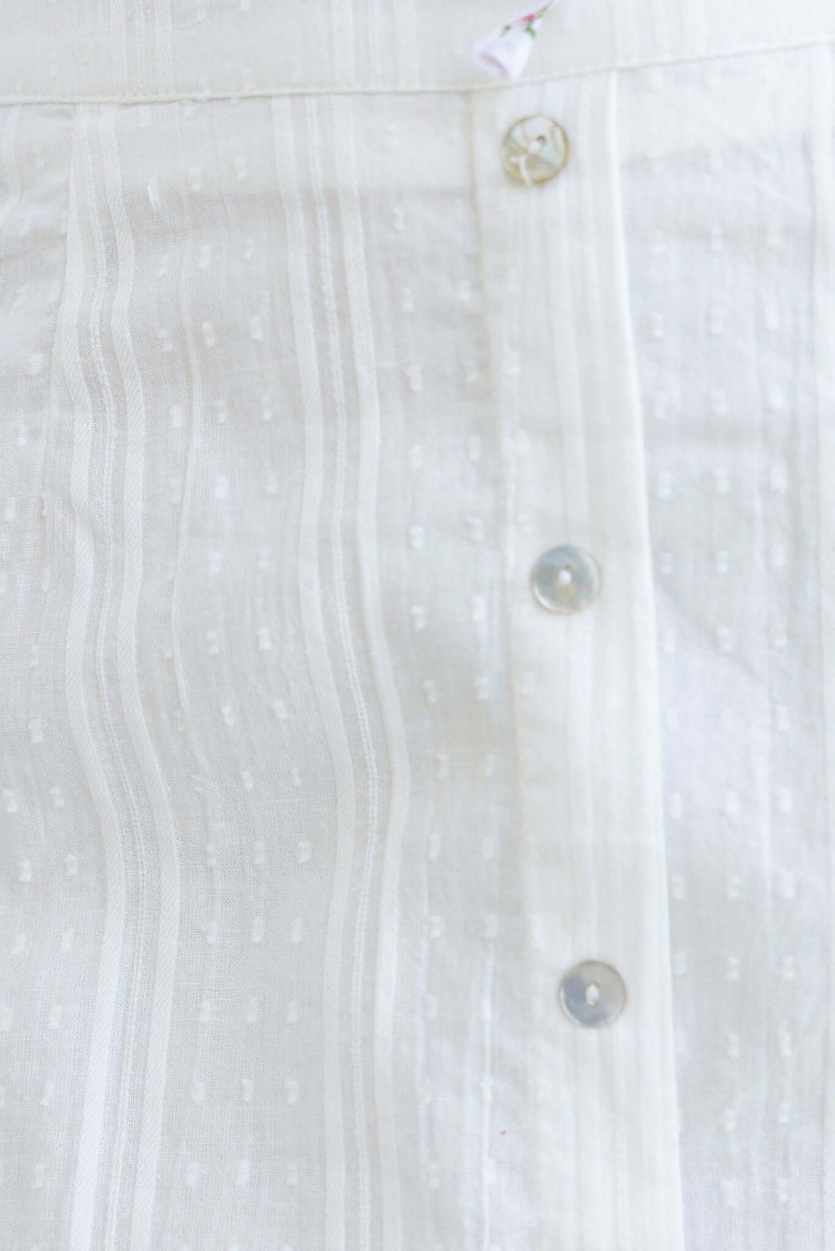 Close-up of the Nove Skirt showcasing faux buttons and textured fabric in a light tone.