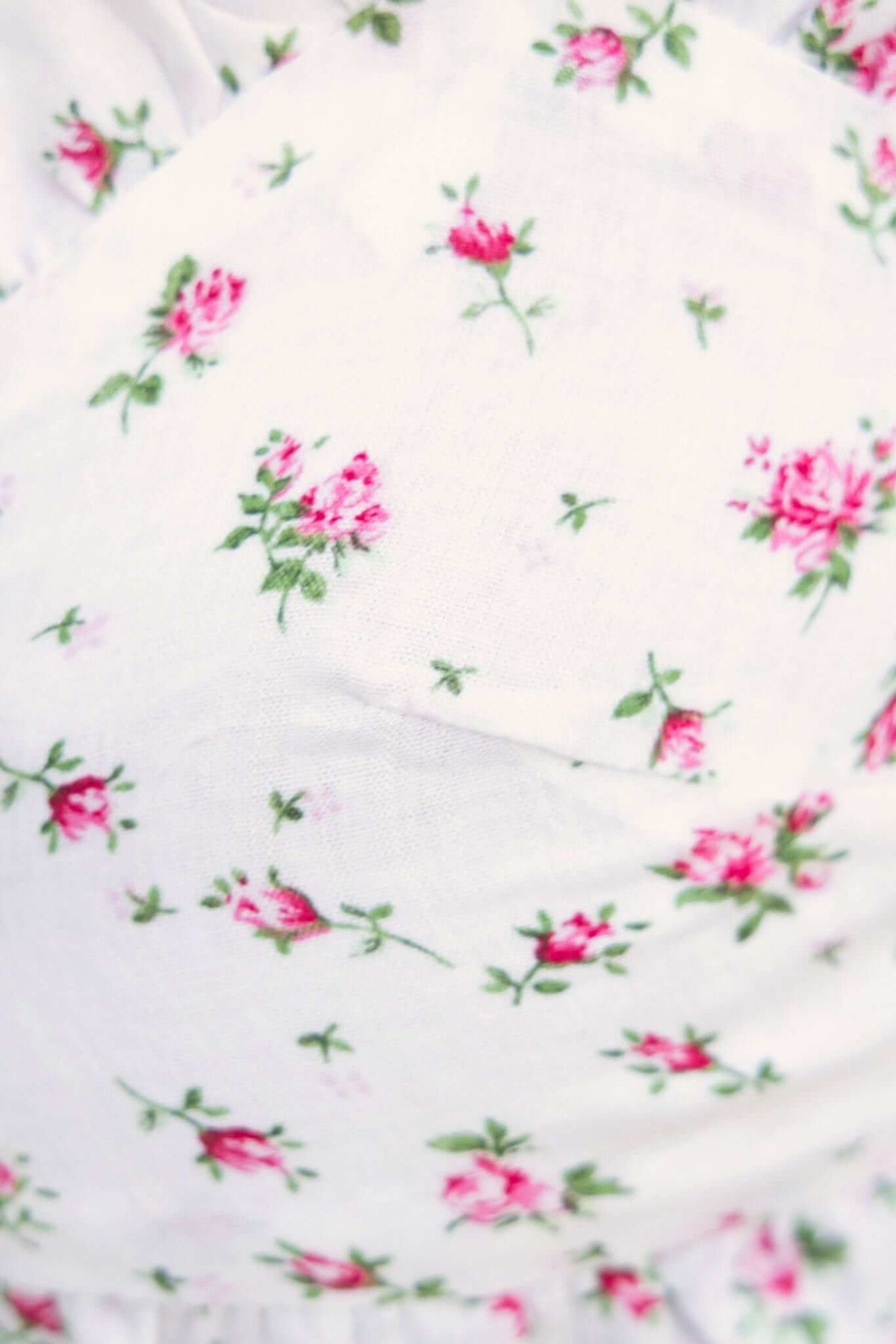 Close-up of floral fabric with pink roses on a white background, perfect for the Soreia Top.