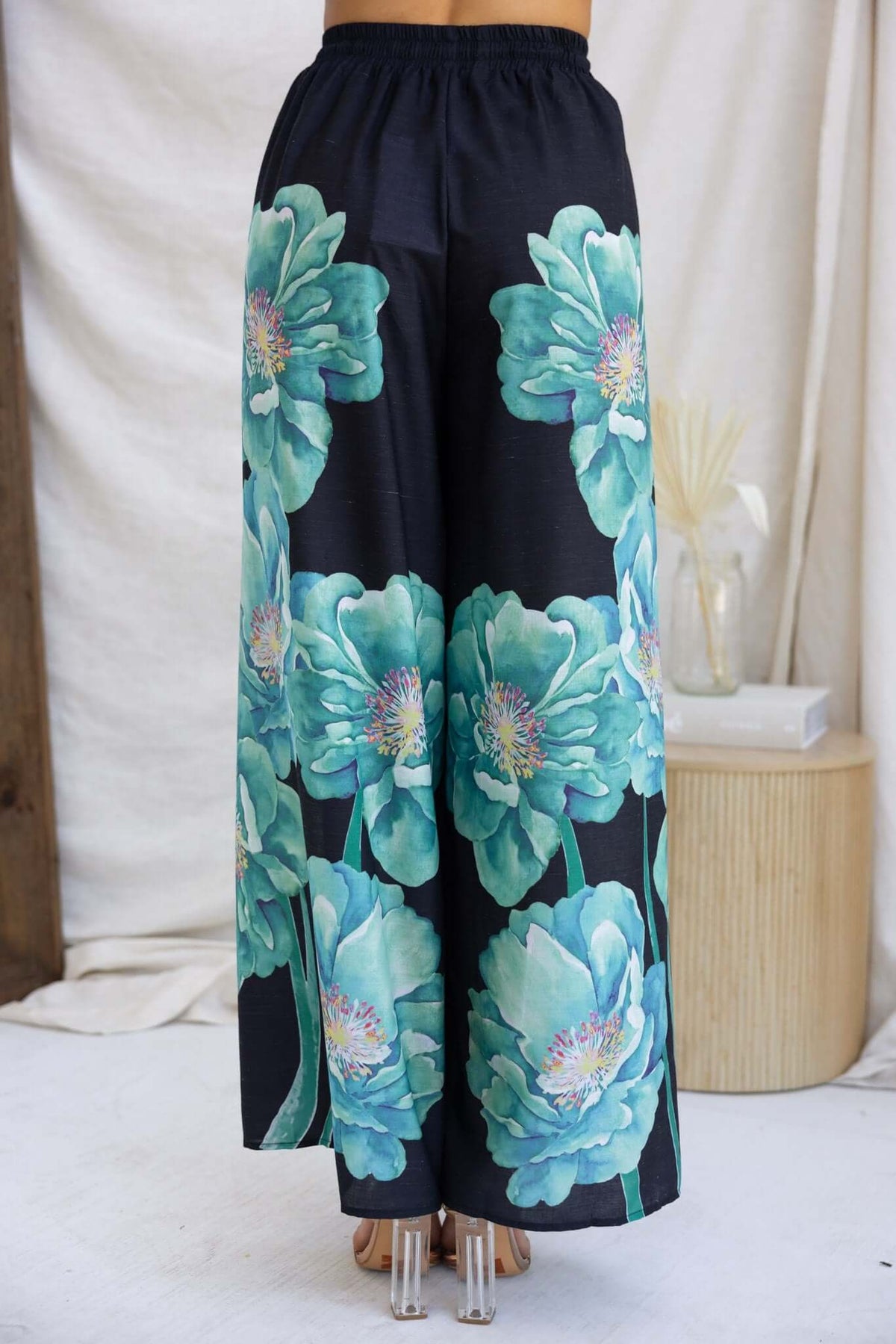 Floral wide-leg pants with blue flowers on a black background, featuring an elastic waistband and lightweight fabric.
