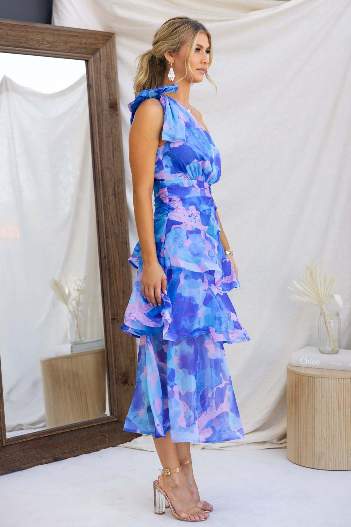 Model wearing a Sherbert Midi Dress with a one-shoulder neckline and ruffle hem in blue and pink hues.