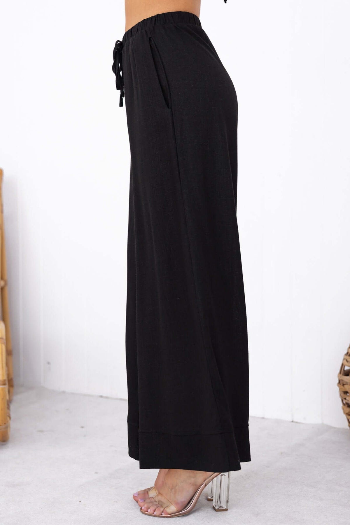 Side view of Frances Pants in black, featuring an elastic waistband and pockets for a relaxed, stylish look.