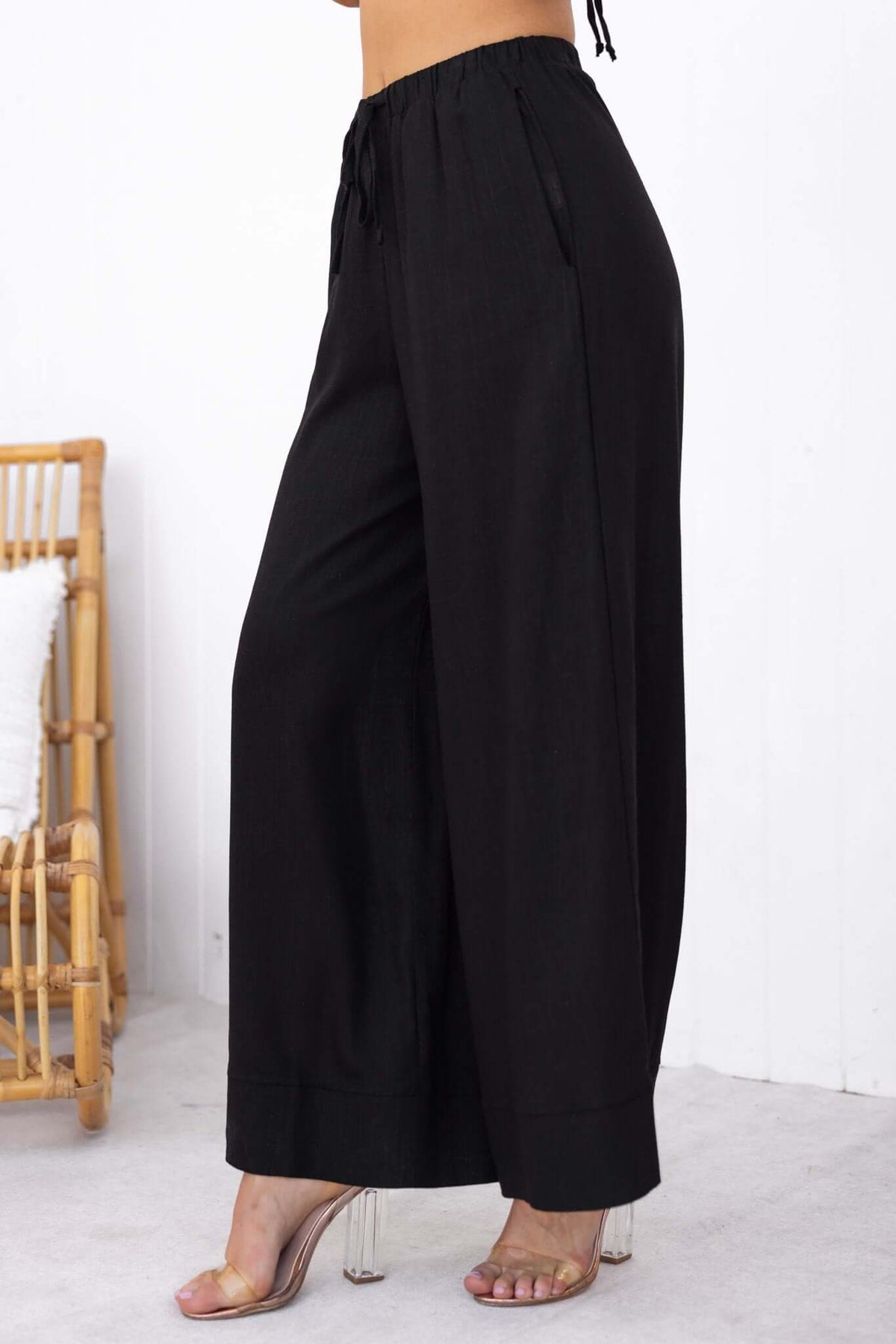 Side view of Frances Pants in black, featuring an elastic waistband and pockets, styled with a relaxed fit.