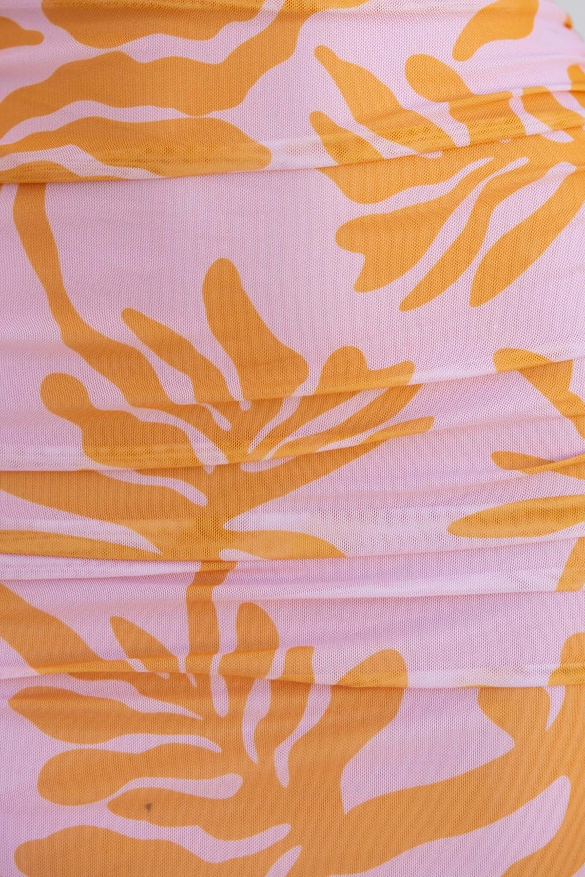 Floral print fabric detail of the Giorgi Maxi Dress featuring orange leaf patterns on a pink background.