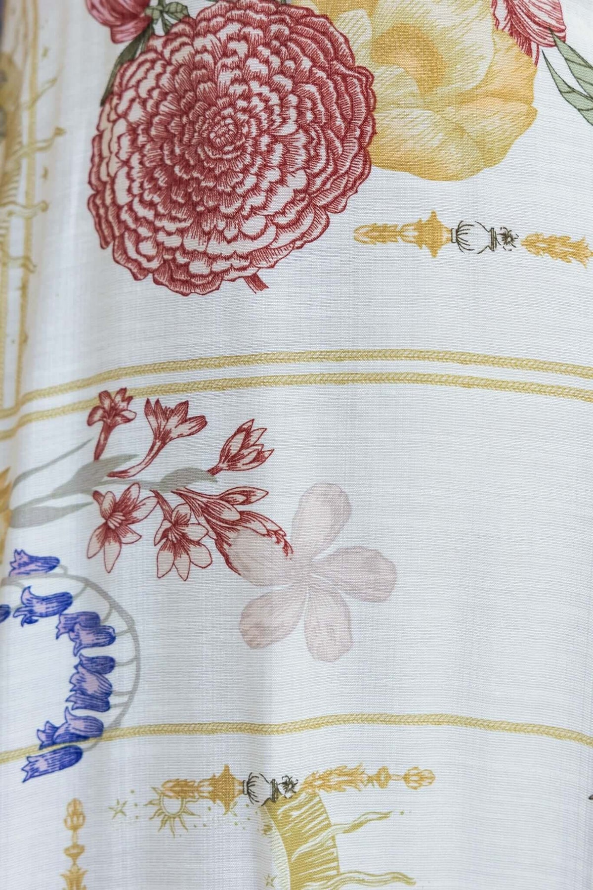 Close-up of floral patterns featuring red, yellow, and pink flowers on a light background in the Salilah Maxi Dress.