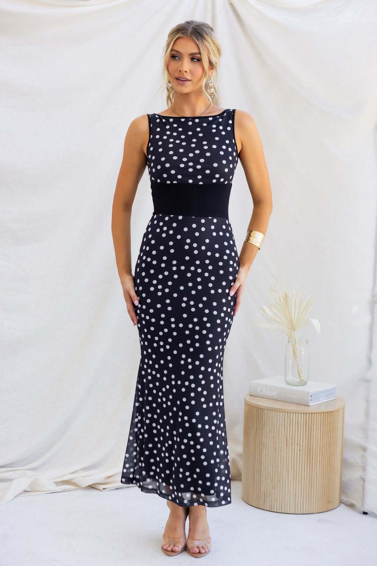 Elegant black and white polka dot maxi dress with a fitted waist, showcasing a boat neckline and mesh material.